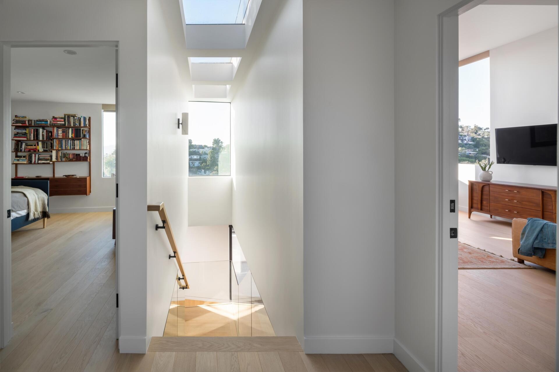 The long series of skylights filters light intro the staircase, cuts through the center of the home, creating a clear line from front to back. This “slot” pulls daylight deep inside and links the different spaces in a subtle way.