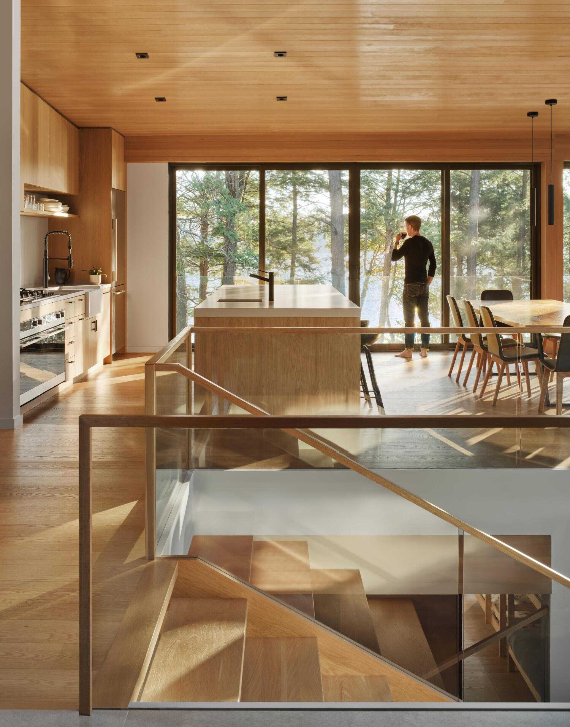A light-filled staircase connects upper living spaces to private rooms below, maintaining a continuous sense of openness throughout the home.