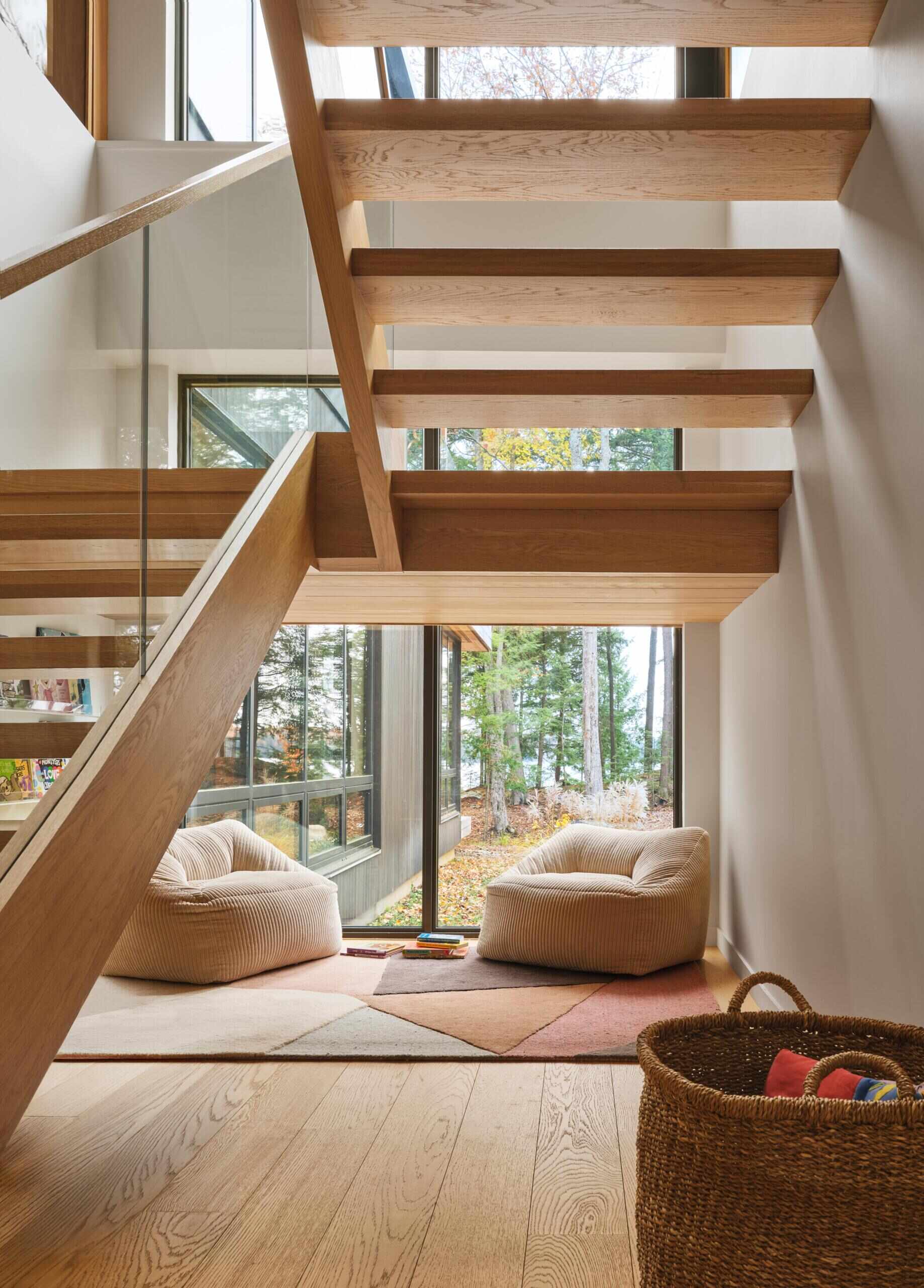 A cozy nook beneath the stairs with soft seating and forest views creates a tucked-away space that feels both playful and inviting.