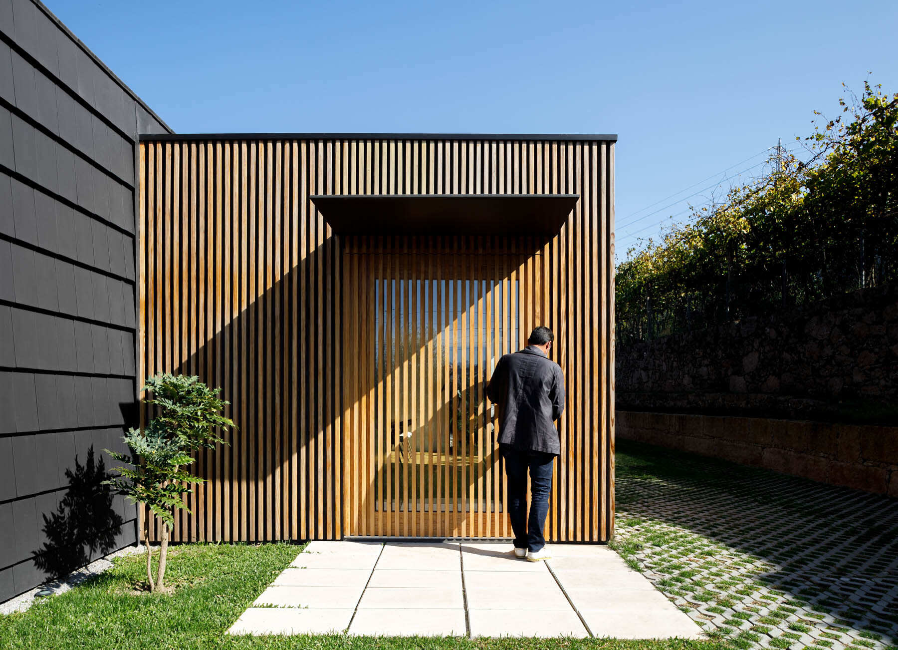 Hidden windows and doors sit behind movable wood slats, creating a seamless facade that reveals itself only when opened.