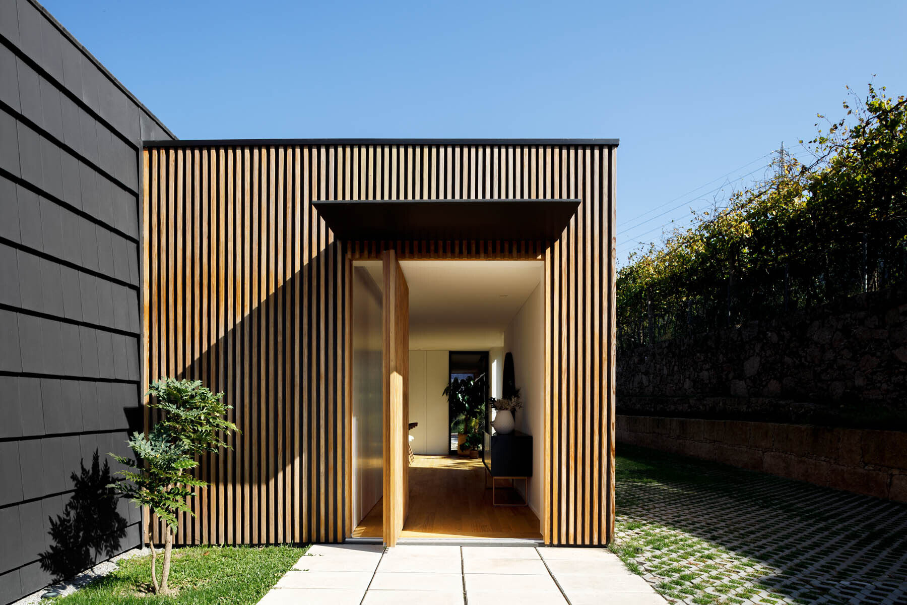 Hidden windows and doors sit behind movable wood slats, creating a seamless facade that reveals itself only when opened.