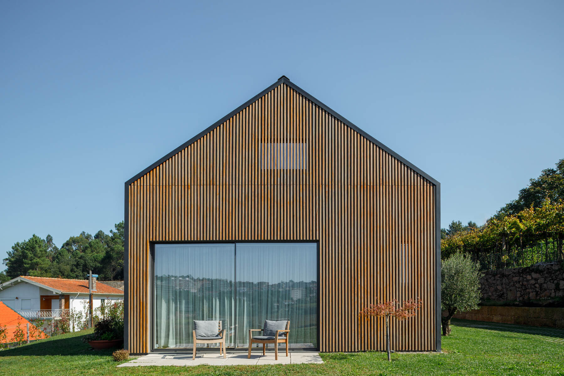 Wood slats wrap the exterior of this home, creating a clean facade that shifts between solid and open as you move around it.