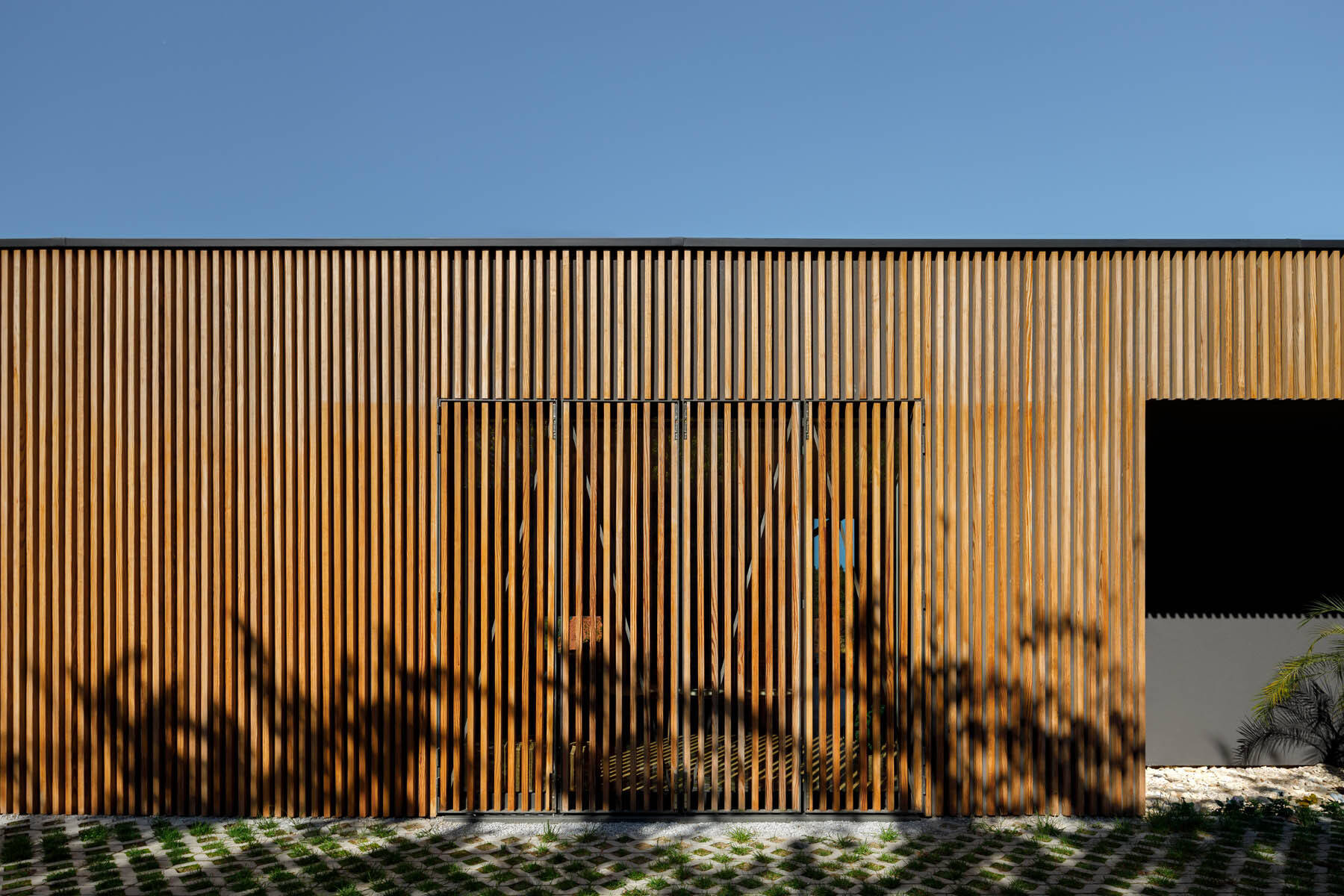 Hidden windows and doors sit behind movable wood slats, creating a seamless facade that reveals itself only when opened.