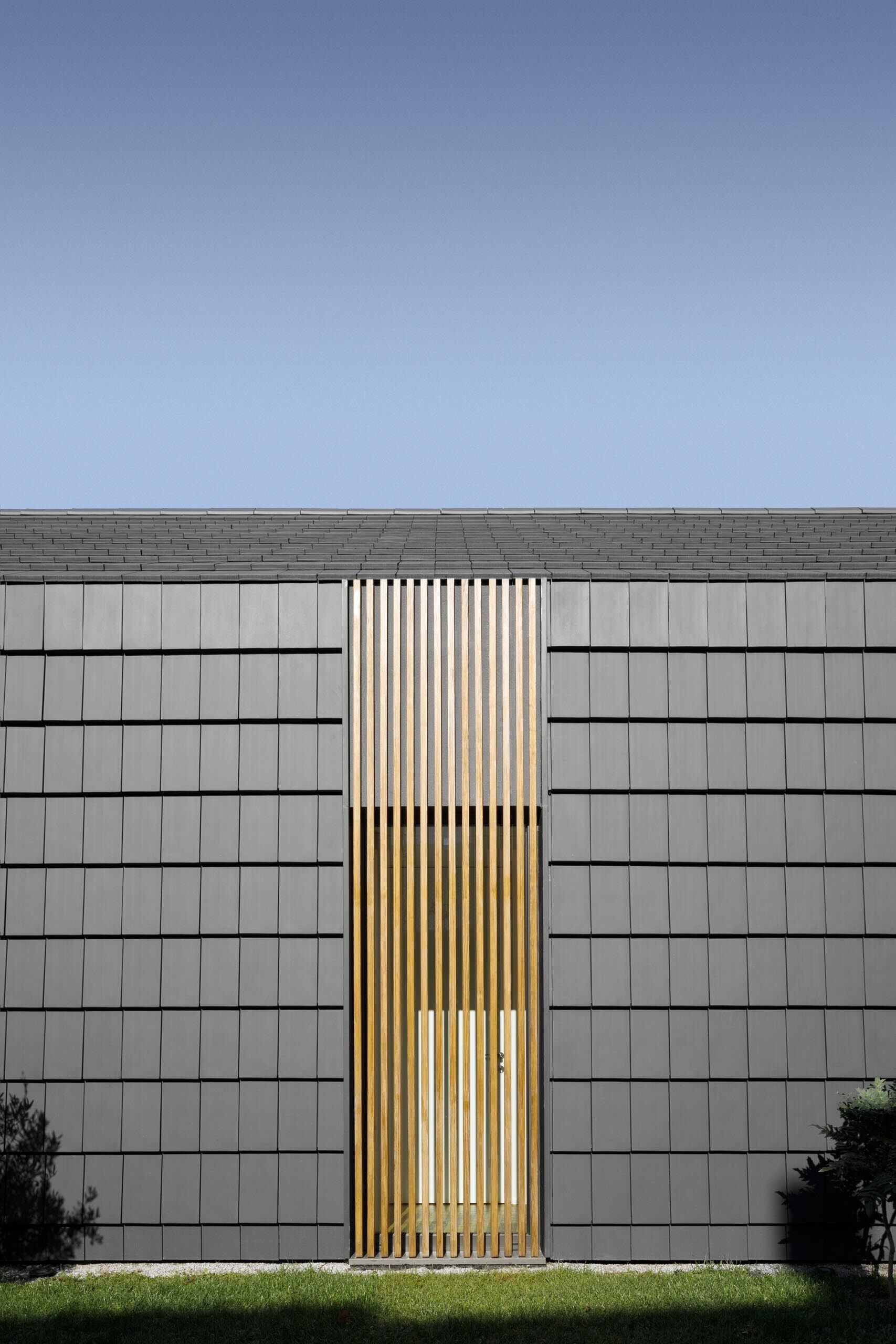 Hidden windows and doors sit behind movable wood slats, creating a seamless facade that reveals itself only when opened.