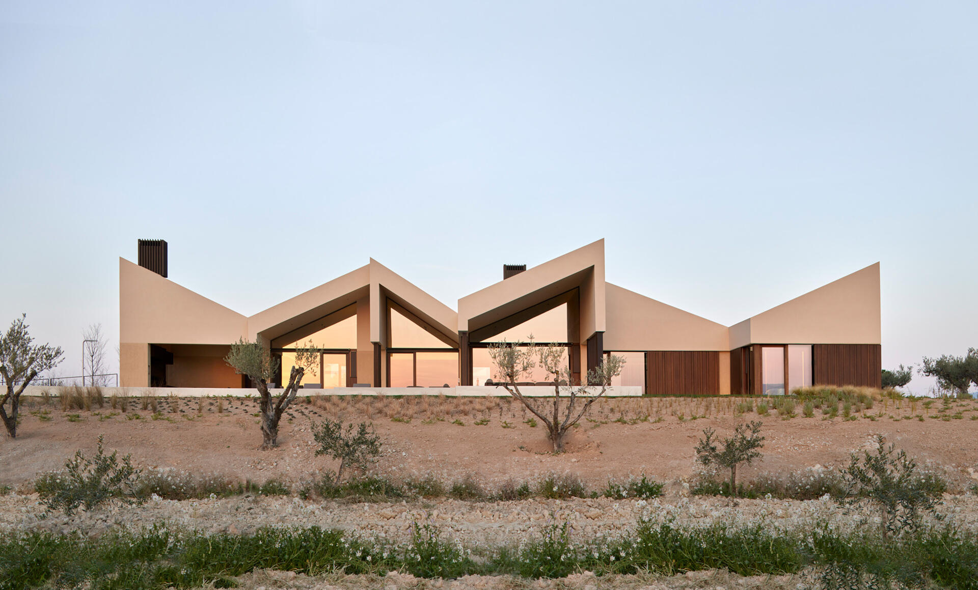 A contemporary home in Valencia reimagines traditional gable roofs with shifting volumes, textured stucco, and a soft, earthy palette that blends into the hillside.