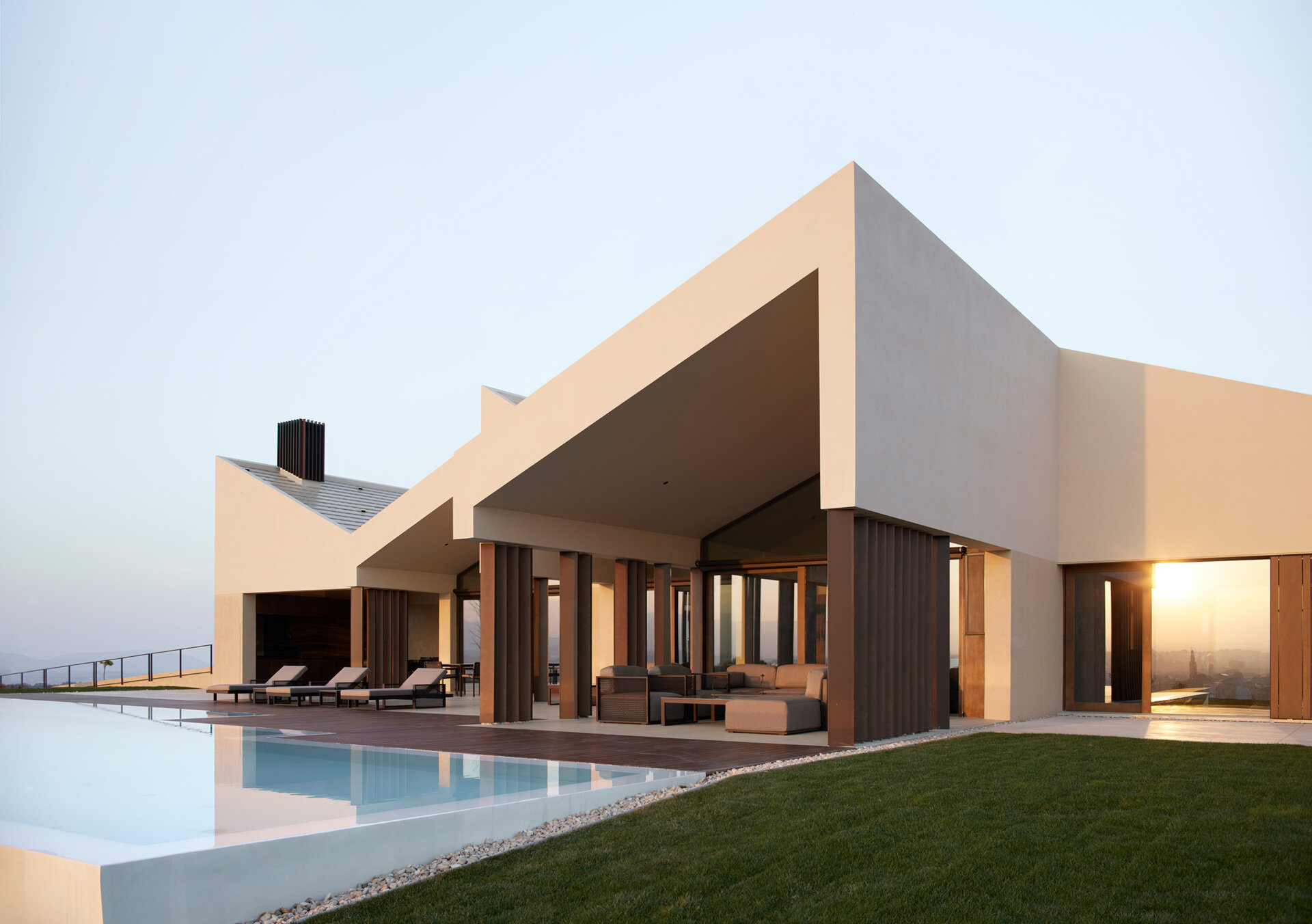 A contemporary home in Valencia reimagines traditional gable roofs with shifting volumes, textured stucco, and a soft, earthy palette that blends into the hillside.