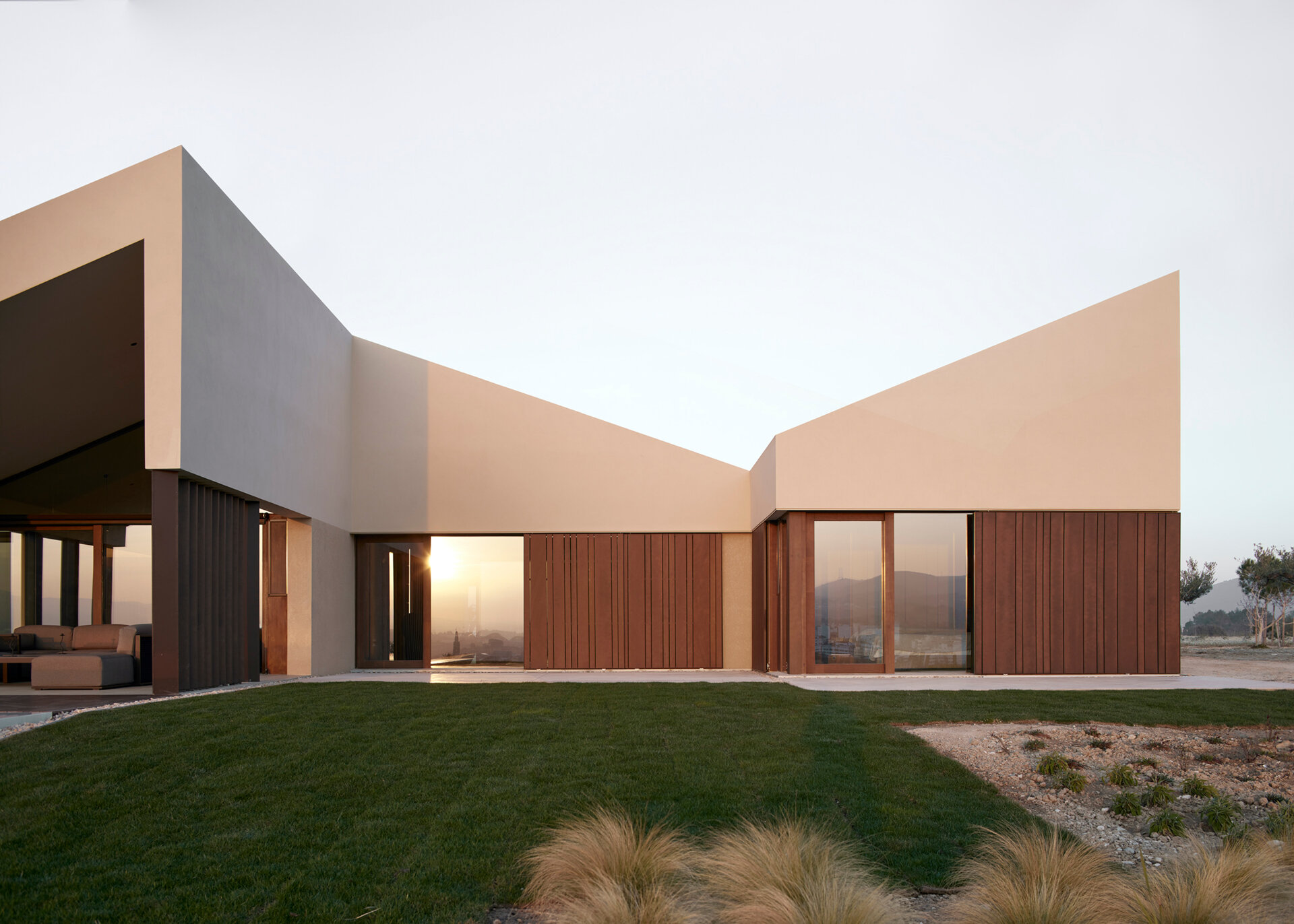 A contemporary home in Valencia reimagines traditional gable roofs with shifting volumes, textured stucco, and a soft, earthy palette that blends into the hillside.
