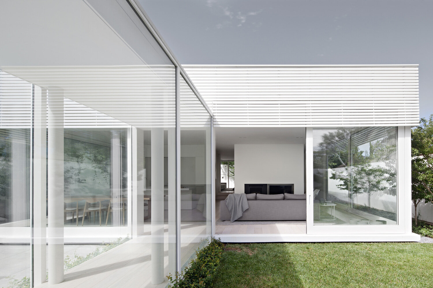This long window lined hallway guides you through an interior garden and pool before reaching the living space, turning arrival into an experience rather than a doorway.