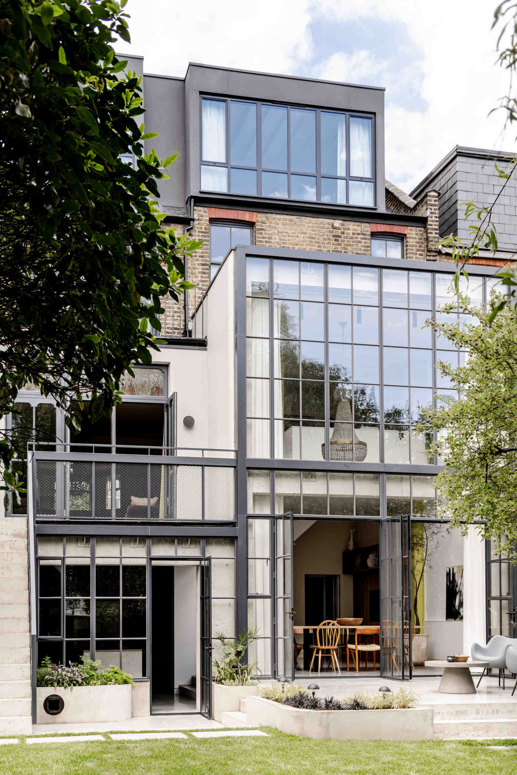 The architecture of House of Panes combines exposed concrete and slender steel glazing in a double-height extension, creating a contemporary addition that responds to the historic Edwardian terrace.