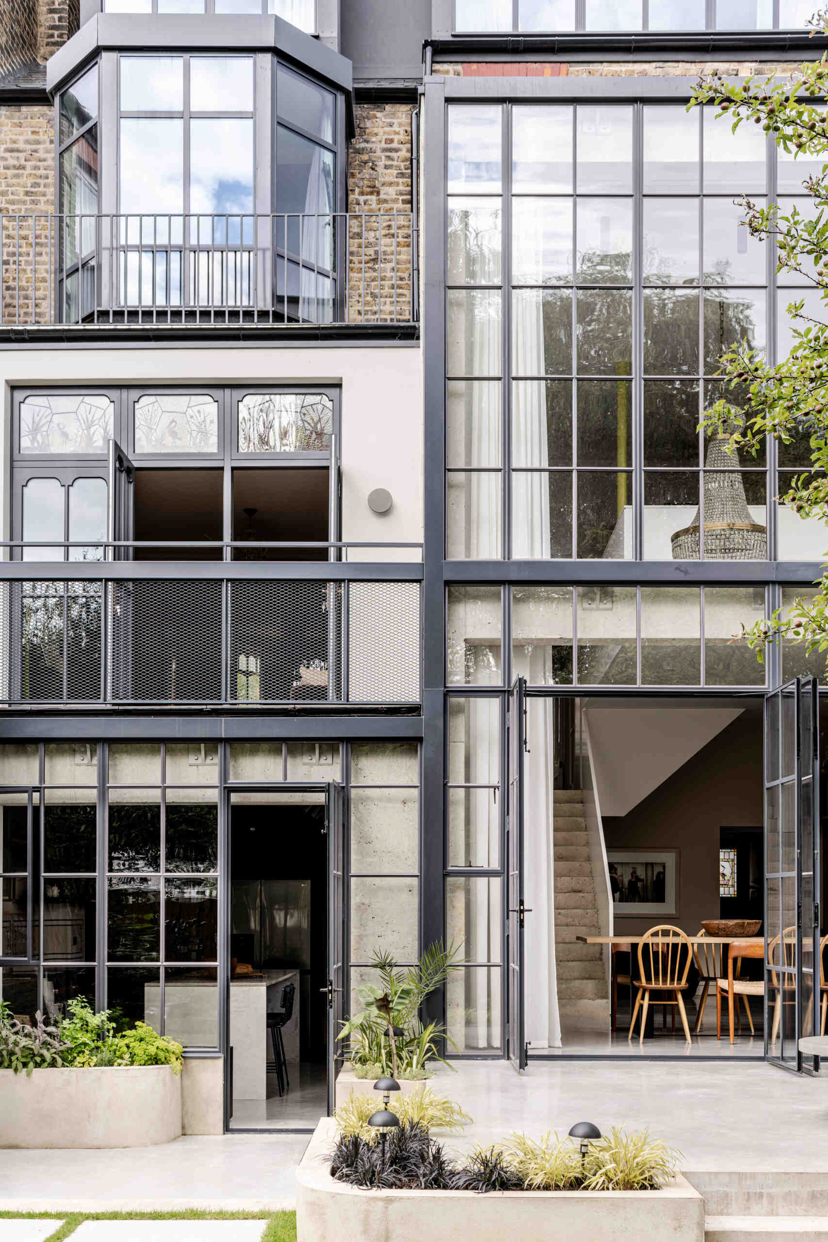 The architecture of House of Panes combines exposed concrete and slender steel glazing in a double-height extension, creating a contemporary addition that responds to the historic Edwardian terrace.