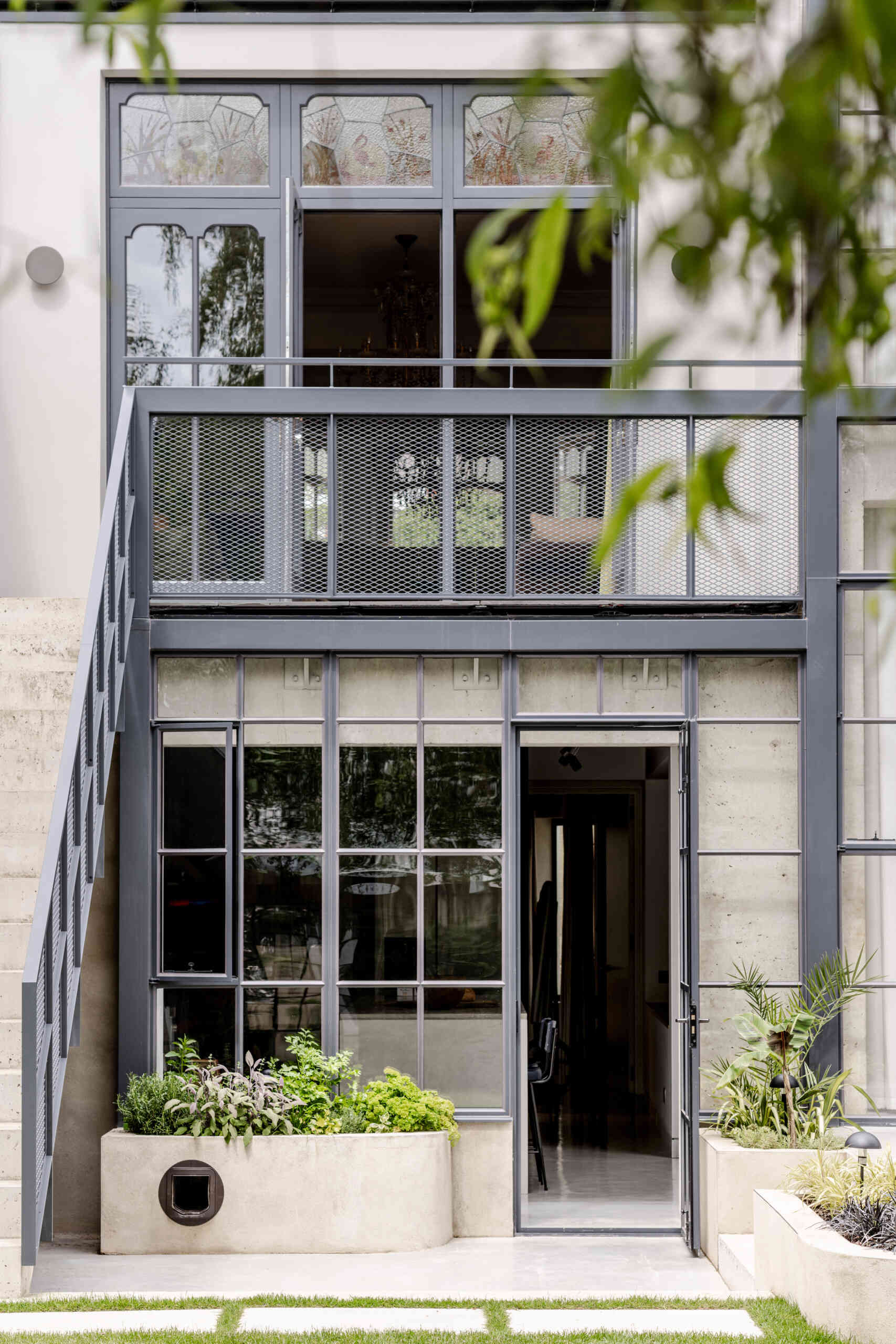 The architecture of House of Panes combines exposed concrete and slender steel glazing in a double-height extension, creating a contemporary addition that responds to the historic Edwardian terrace.