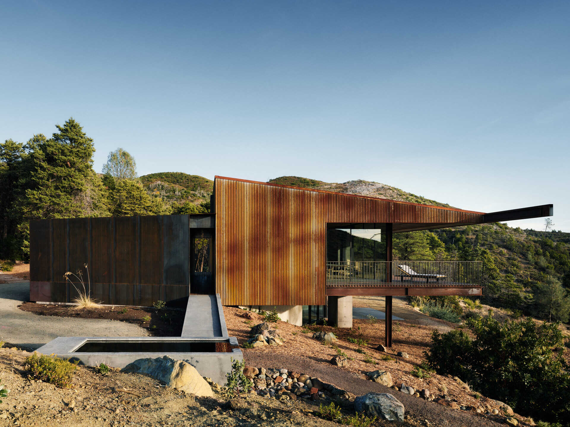 By reusing 90 percent of the original foundation, this home reduces waste while creating a simple, grounded form that follows the ridgeline.