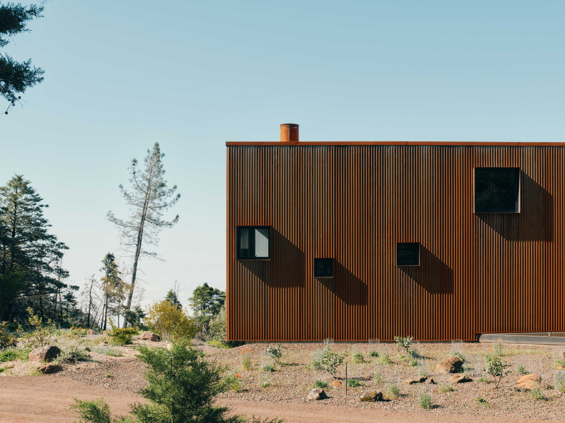 A corten steel exterior, ember screens, and integrated sprinklers work together to protect this home while keeping maintenance low.