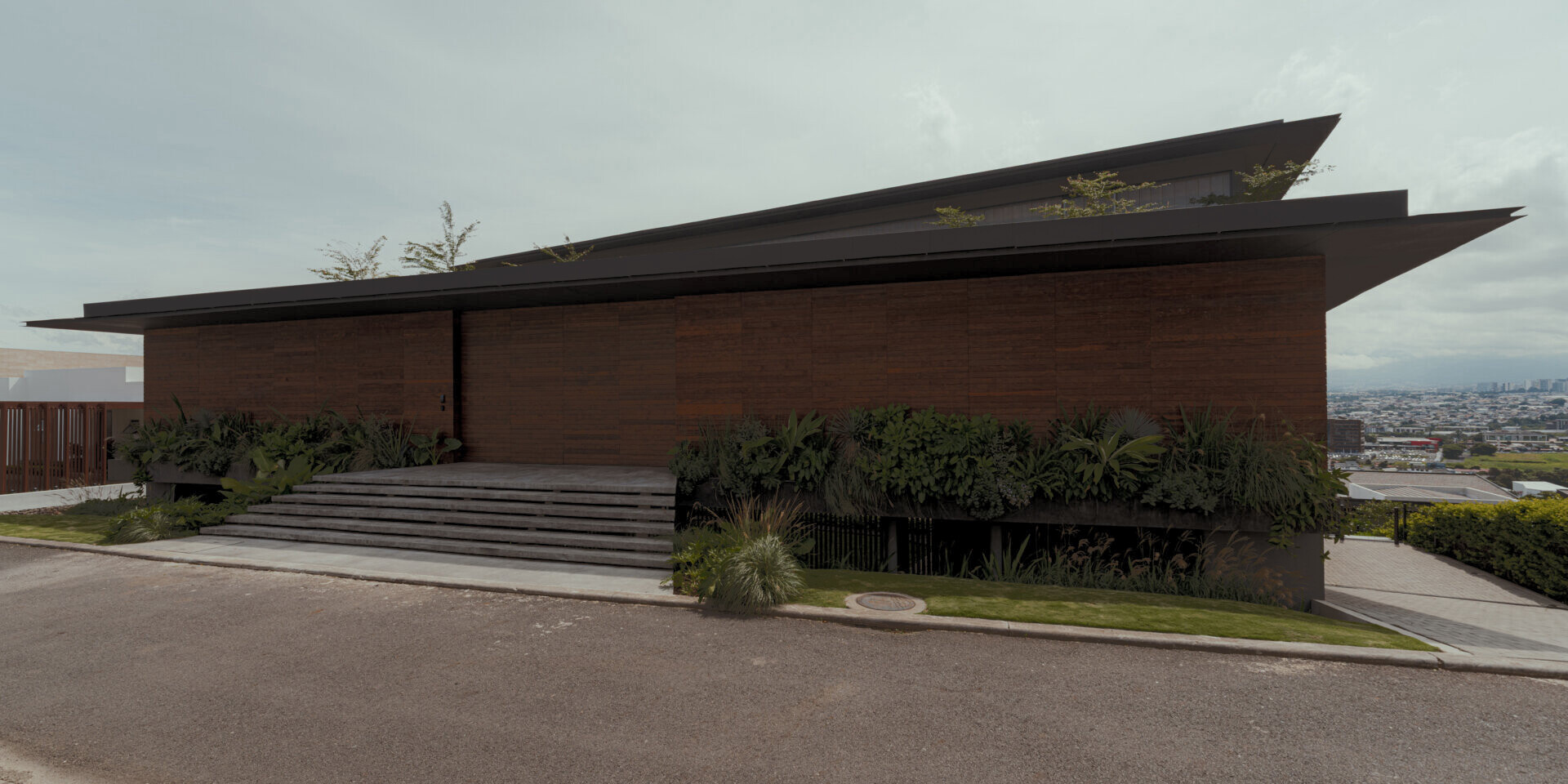 A tiered hillside home in Costa Rica with a central courtyard, open-air spaces, wood slats, and a bridge-like terrace framing expansive valley views.