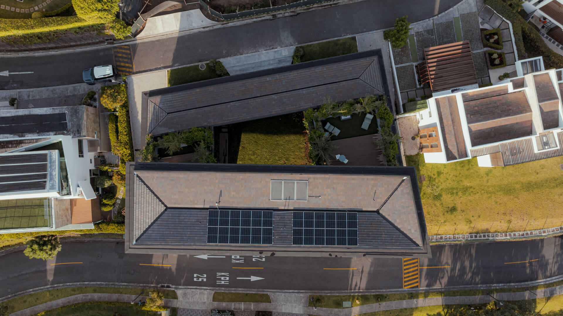 A tiered hillside home in Costa Rica with a central courtyard, open-air spaces, wood slats, and a bridge-like terrace framing expansive valley views.