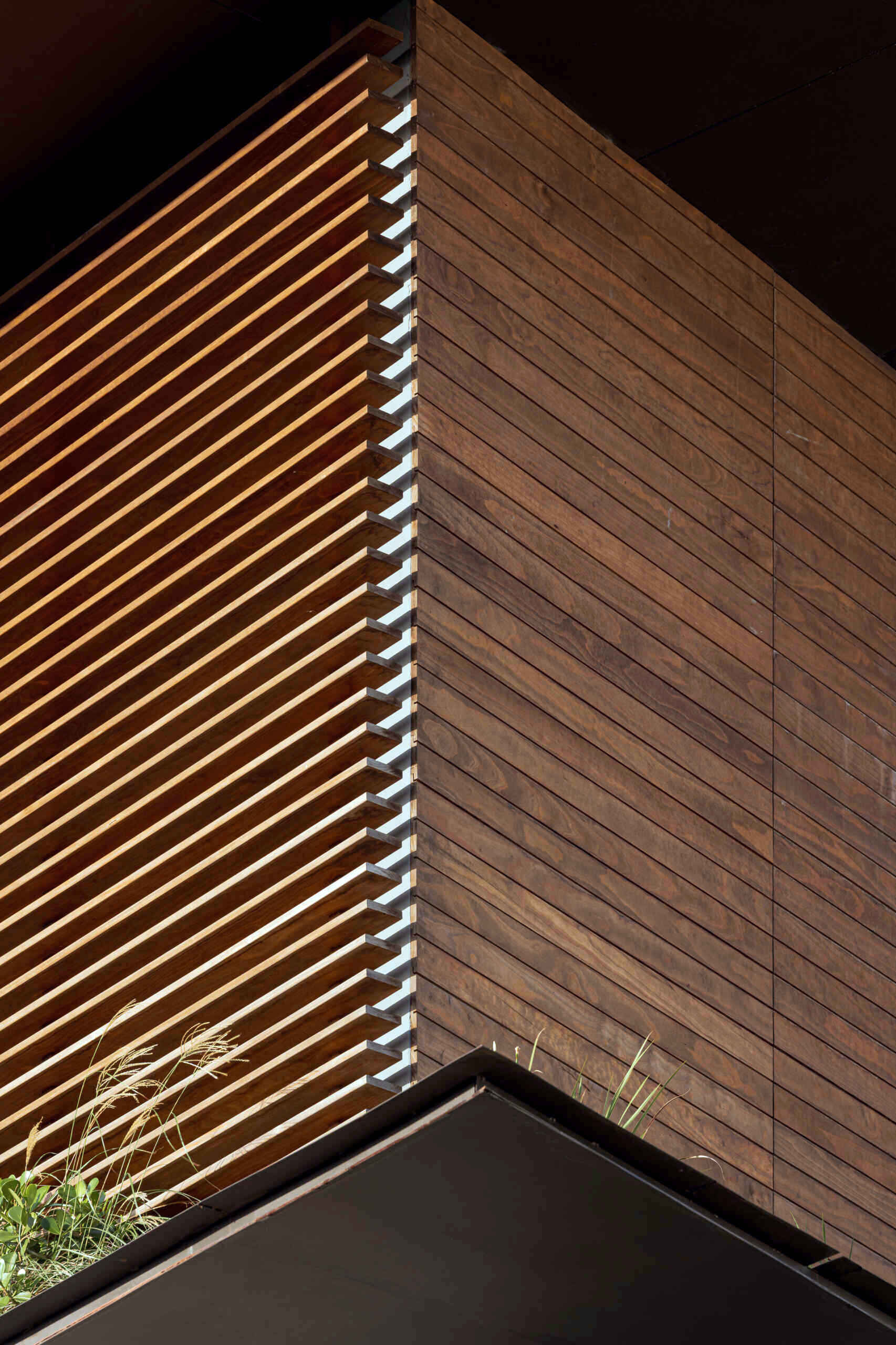 A tiered hillside home in Costa Rica with a central courtyard, open-air spaces, wood slats, and a bridge-like terrace framing expansive valley views.