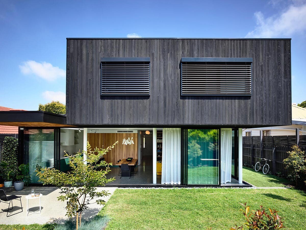 Charred wood upper level shades glass living spaces of this modern home, blending privacy with openness.