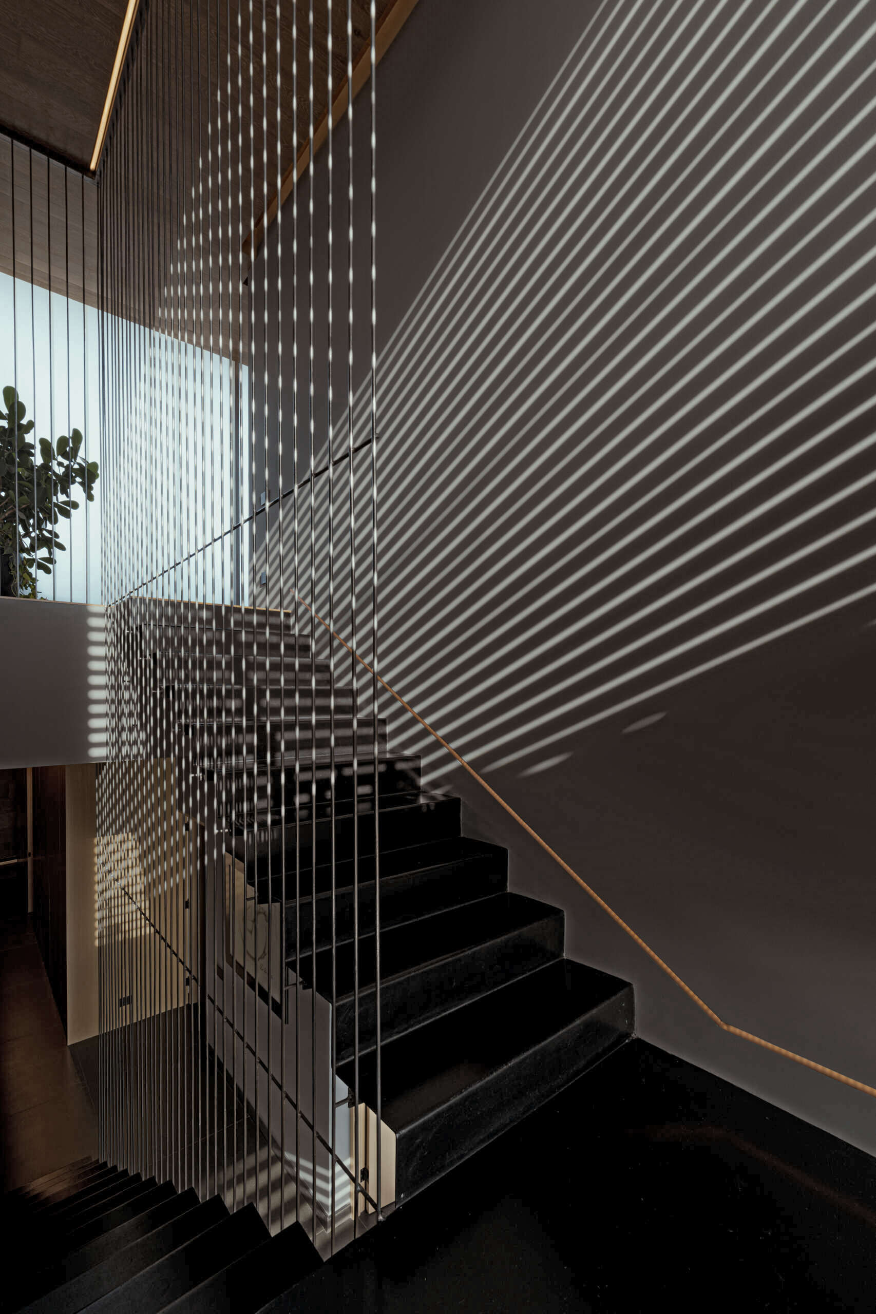 Wood slats on the exterior of the home cast unique shadows on the staircase inside.