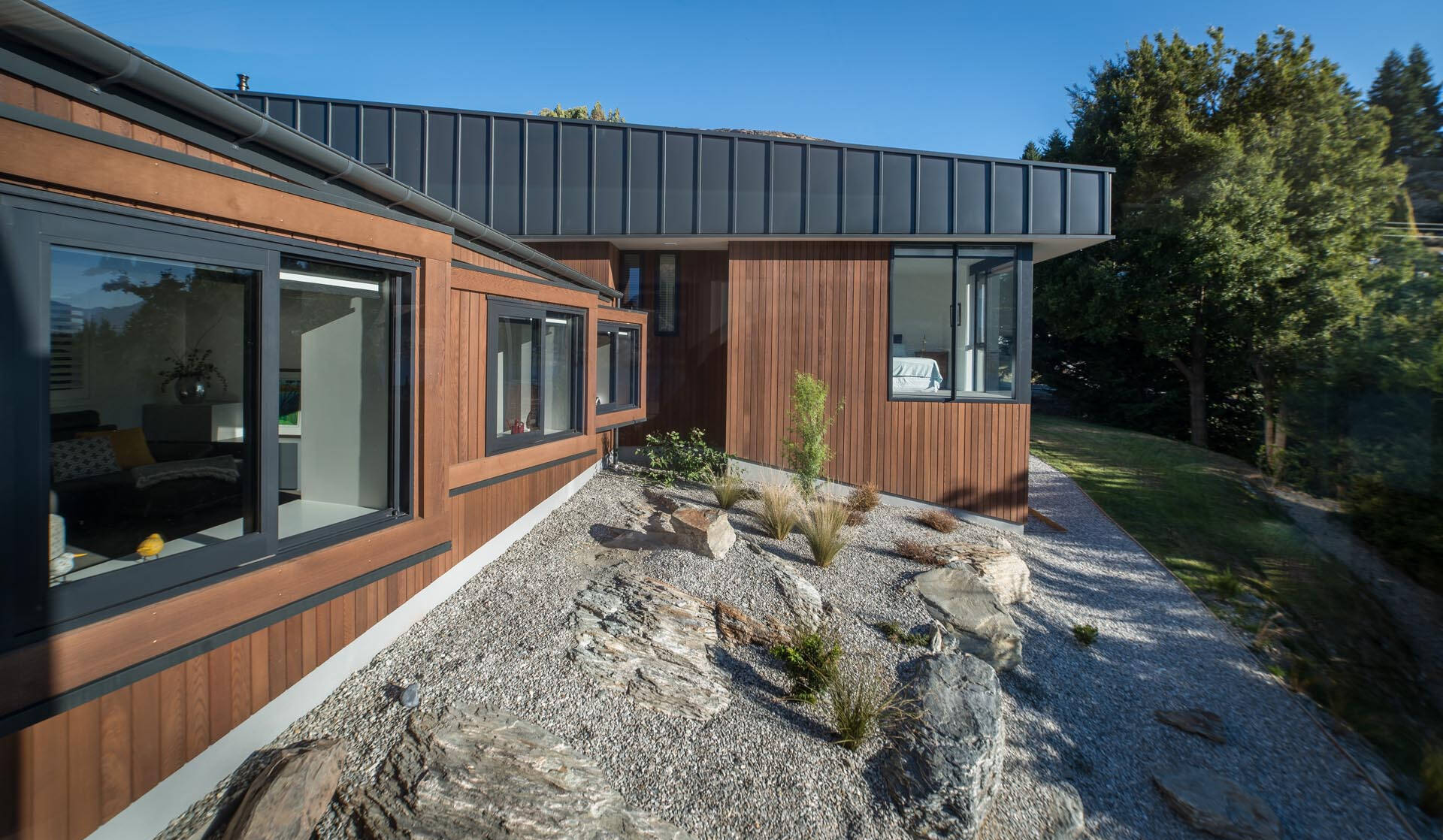 Dos volúmenes en forma de cuña revestidos de madera y metal negro mate se extienden por el empinado sitio de Queenstown mientras enmarcan las vistas del lago Wakatipu.