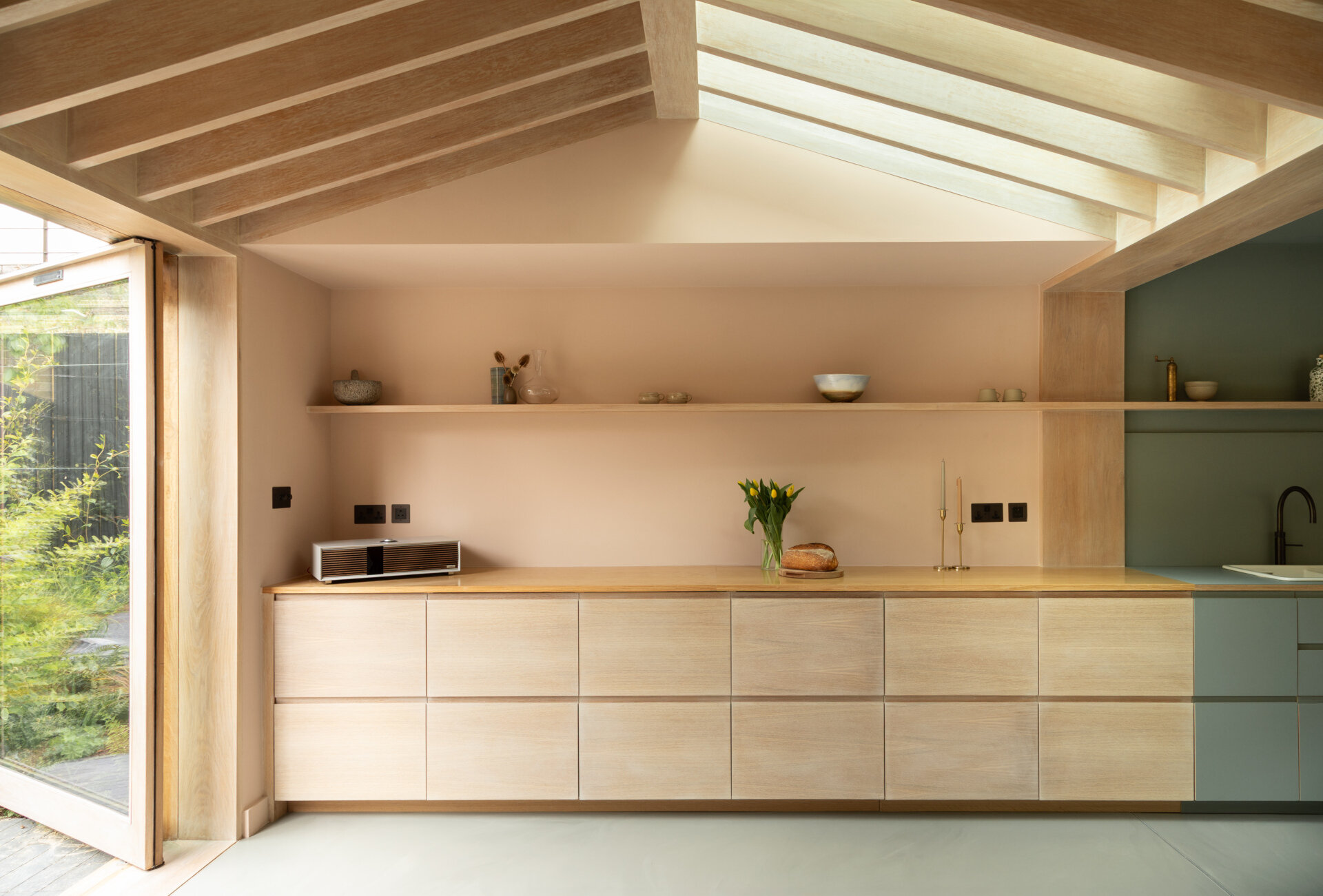 Una extensión inspirada en una cabaña de Turner Architects transforma el borde de un pequeño jardín urbano en un espacio de salón y cocina sólido y basado en materiales.