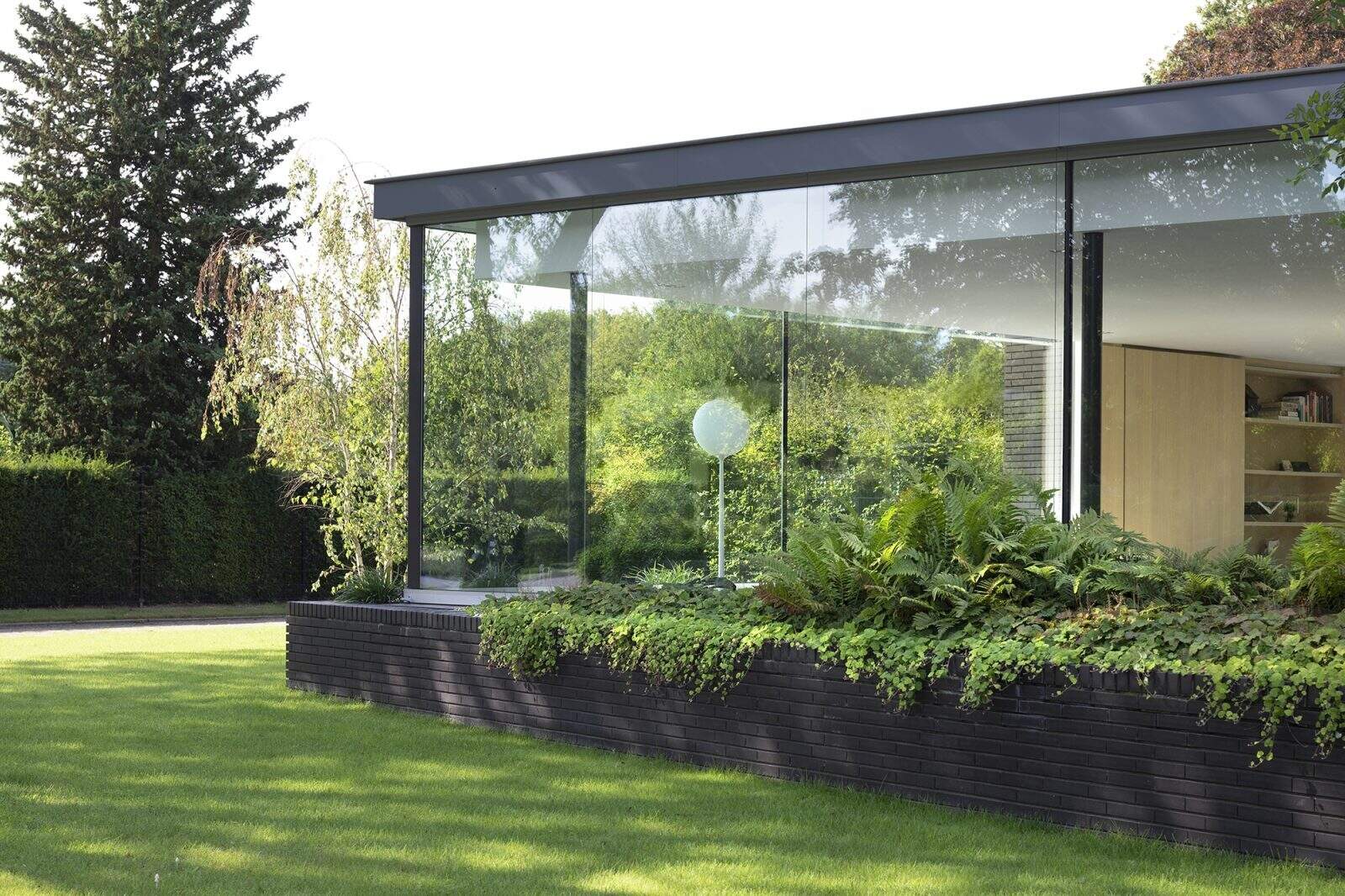 Las paredes de vidrio del piso al techo de esta moderna villa dejan entrar mucha luz mientras conectan cada habitación con los jardines circundantes.