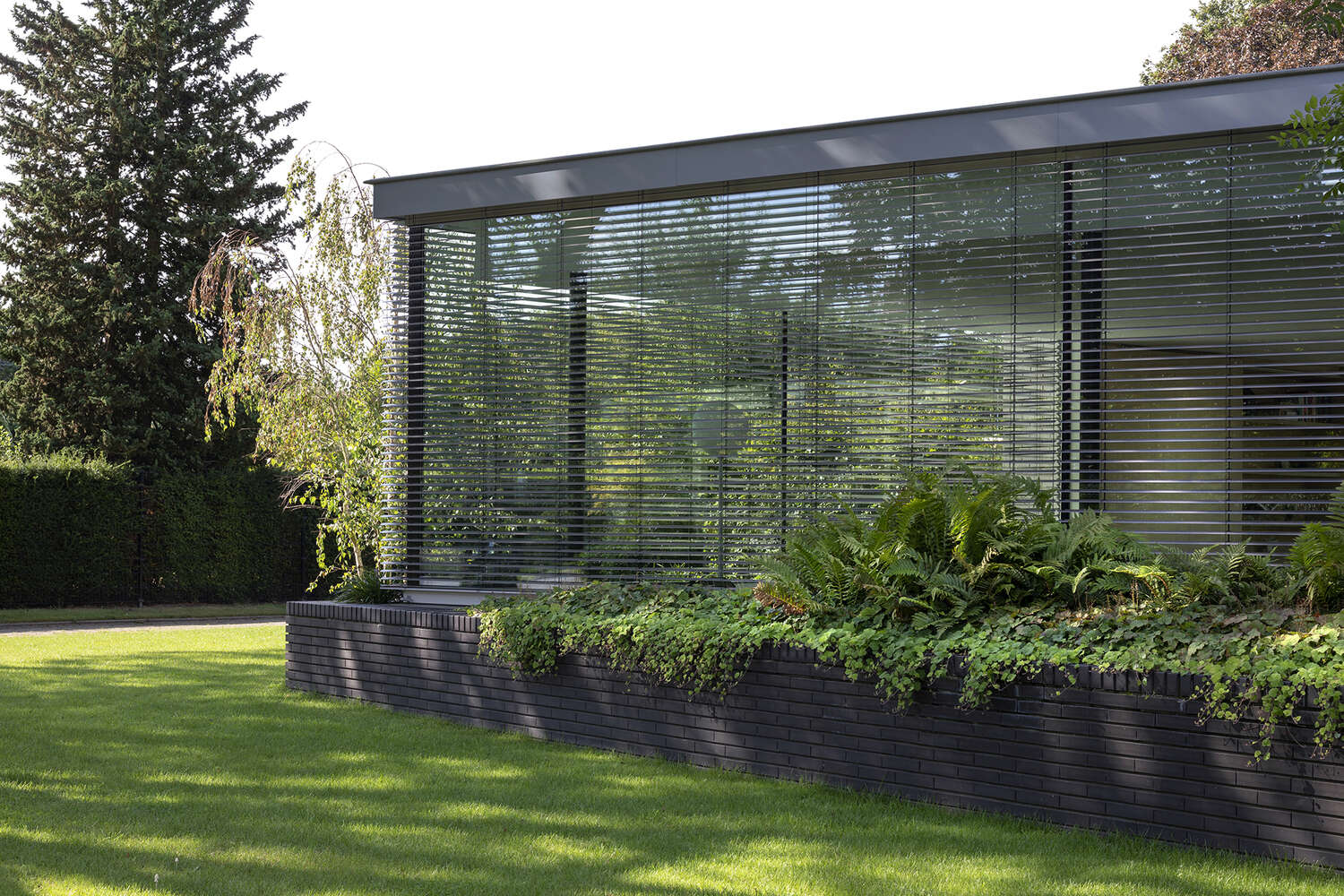 Las paredes de vidrio del piso al techo de esta moderna villa dejan entrar mucha luz mientras conectan cada habitación con los jardines circundantes.