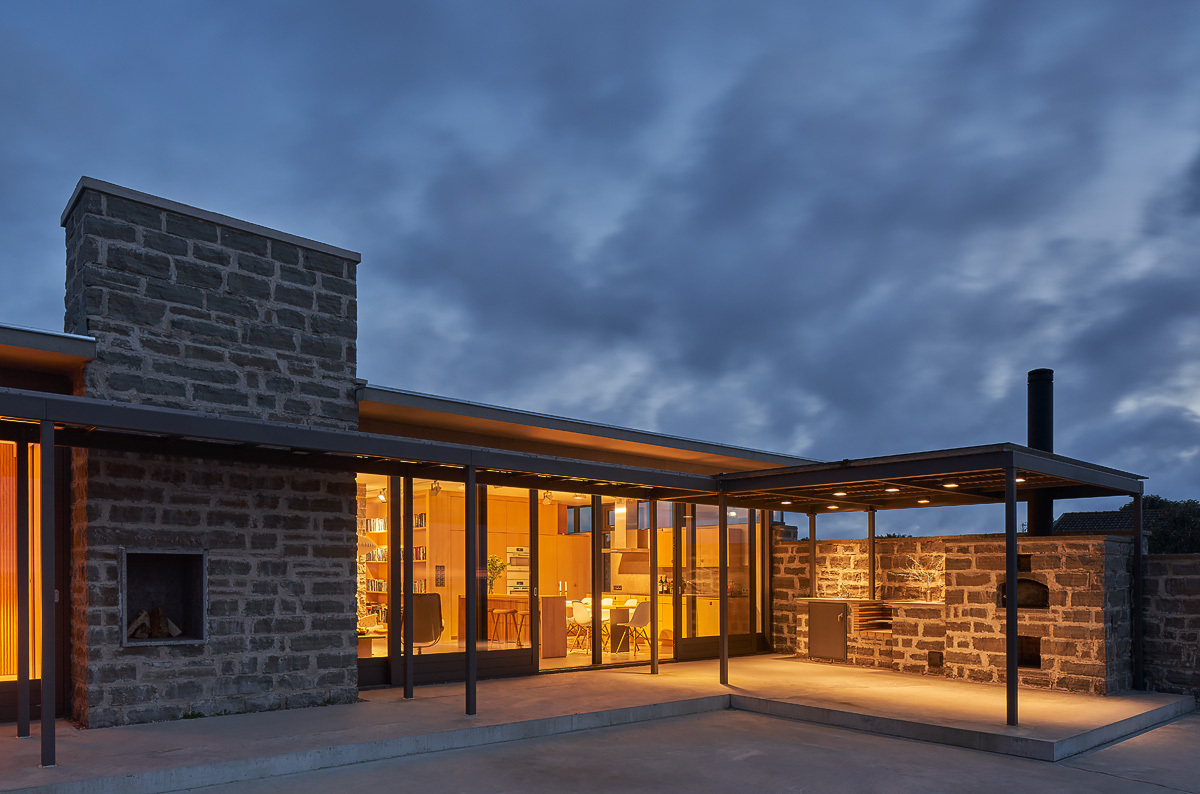 A coastal terrace with an outdoor kitchen and fireplace extends the living space, offering uninterrupted views of the sea.