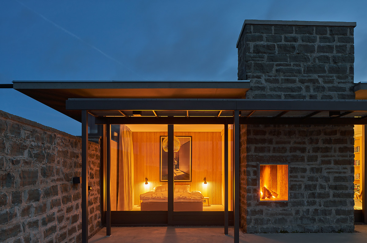 A coastal terrace with an outdoor kitchen and fireplace extends the living space, offering uninterrupted views of the sea.