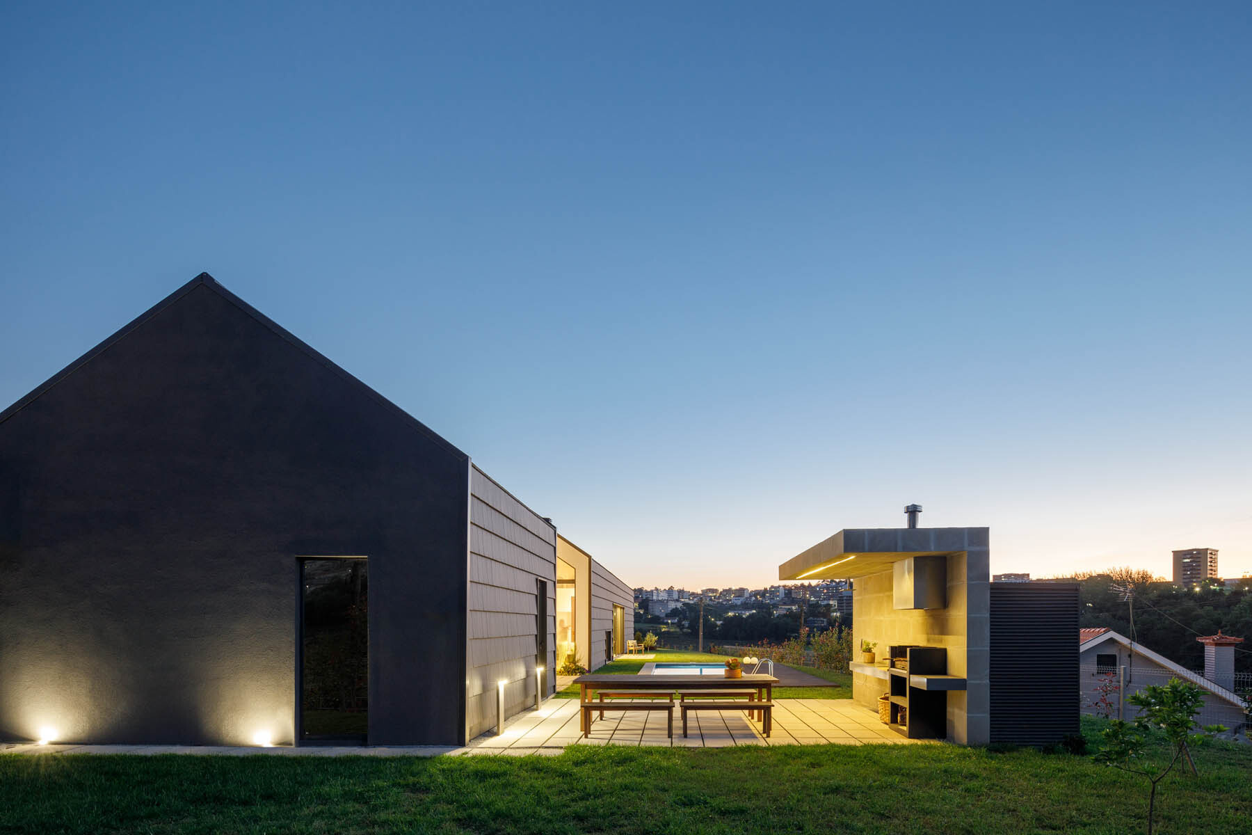 A central void opens the home to a patio, pool, and outdoor dining area, blending indoor living with open air spaces.