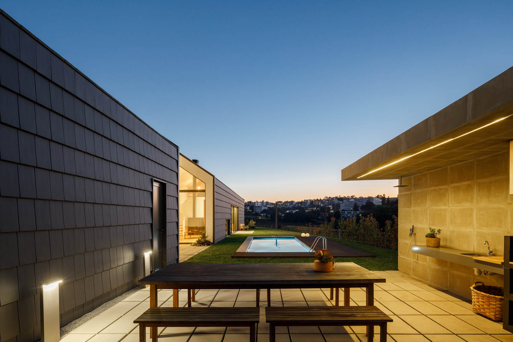 A central void opens the home to a patio, pool, and outdoor dining area, blending indoor living with open air spaces.