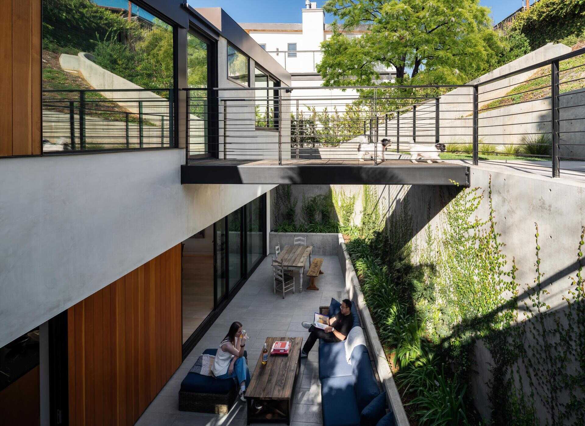 Through more sliding glass doors, and at the rear of the home, the terrace feels more enclosed. Formed by retaining walls, it becomes a quiet outdoor room tucked into the hillside. This space offers a different atmosphere than the front deck, more inward and sheltered.