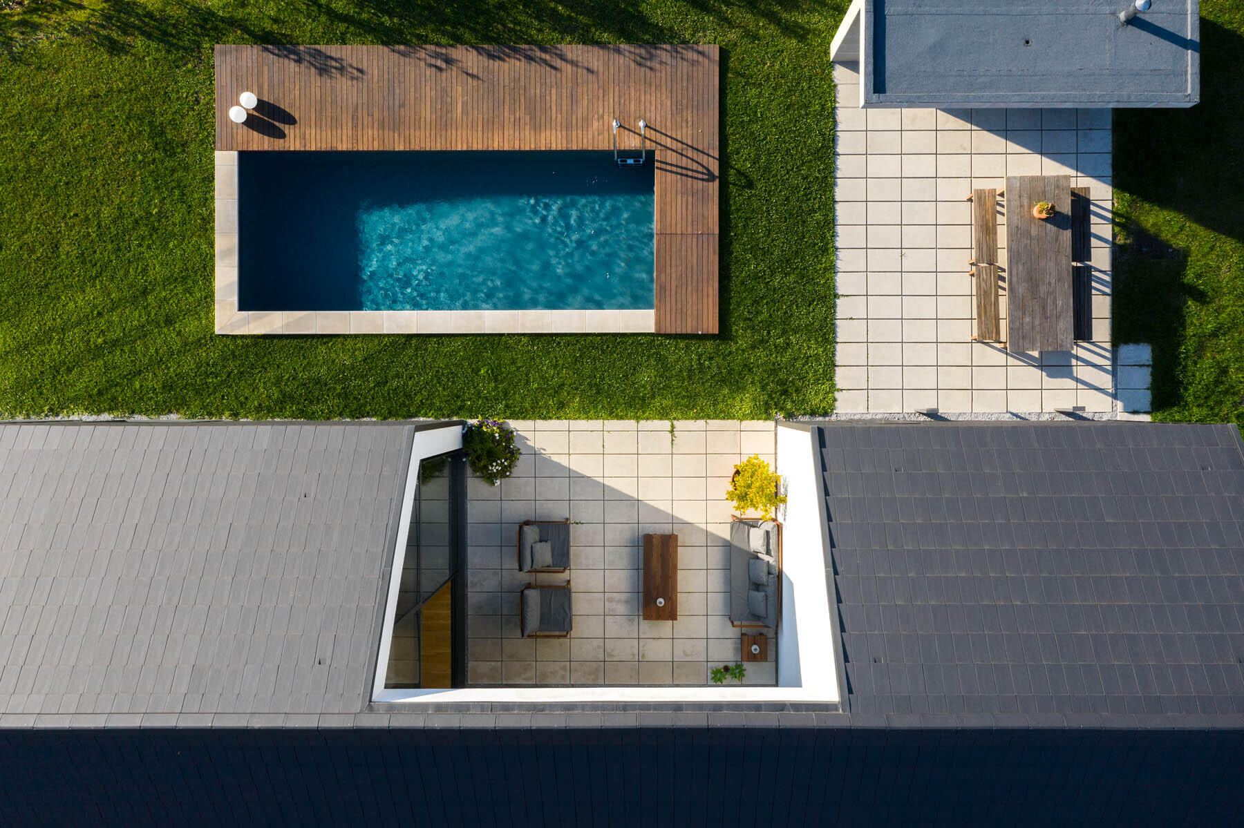 A central void opens the home to a patio, pool, and outdoor dining area, blending indoor living with open air spaces.