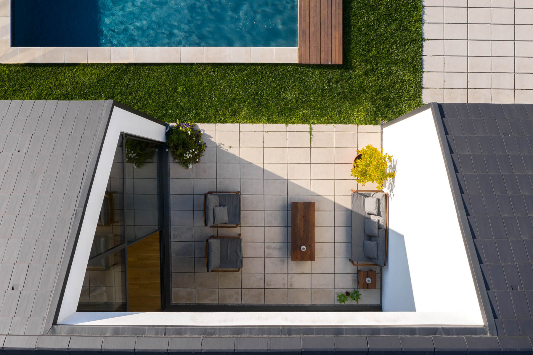 A central void opens the home to a patio, pool, and outdoor dining area, blending indoor living with open air spaces.