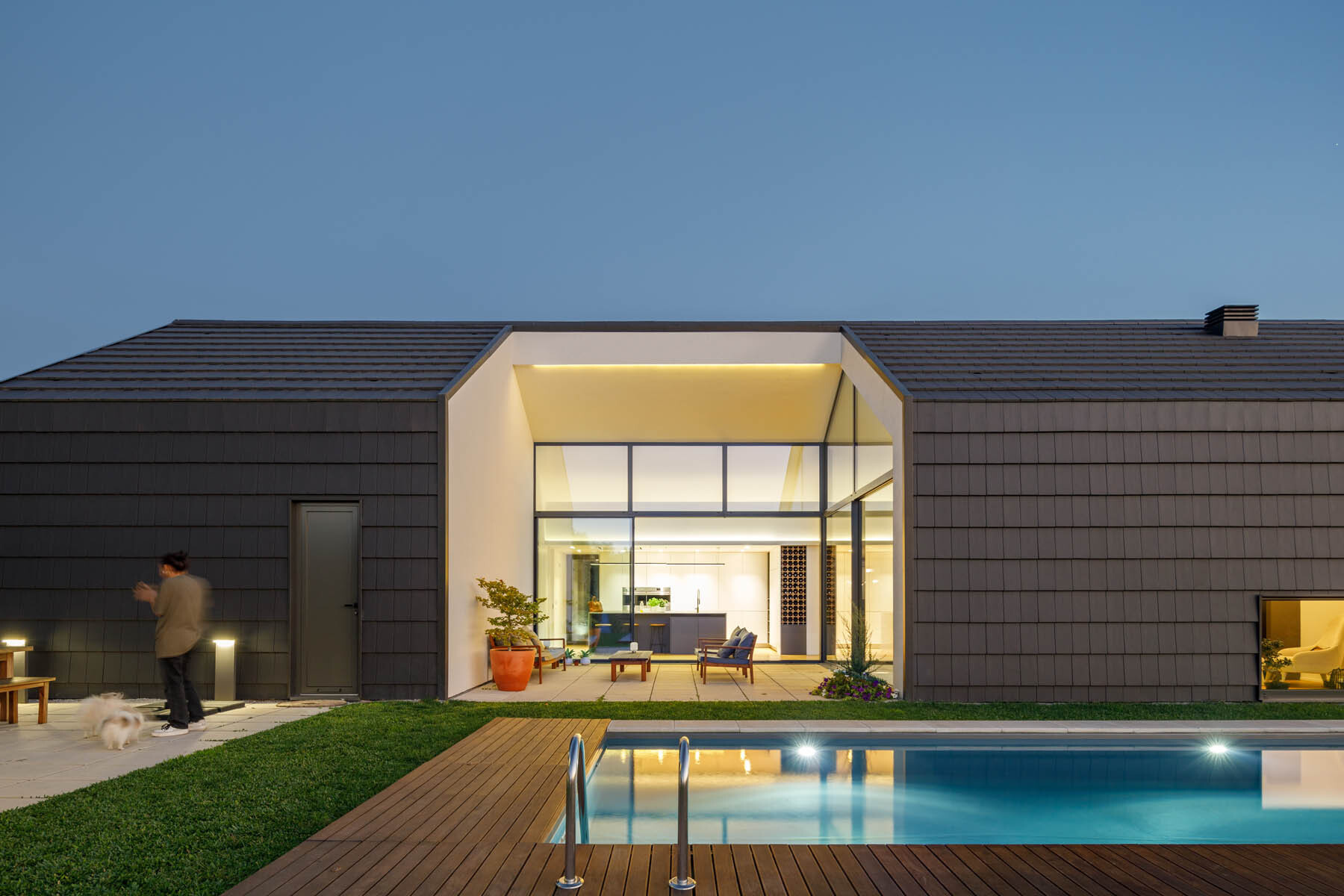 A central void opens the home to a patio, pool, and outdoor dining area, blending indoor living with open air spaces.