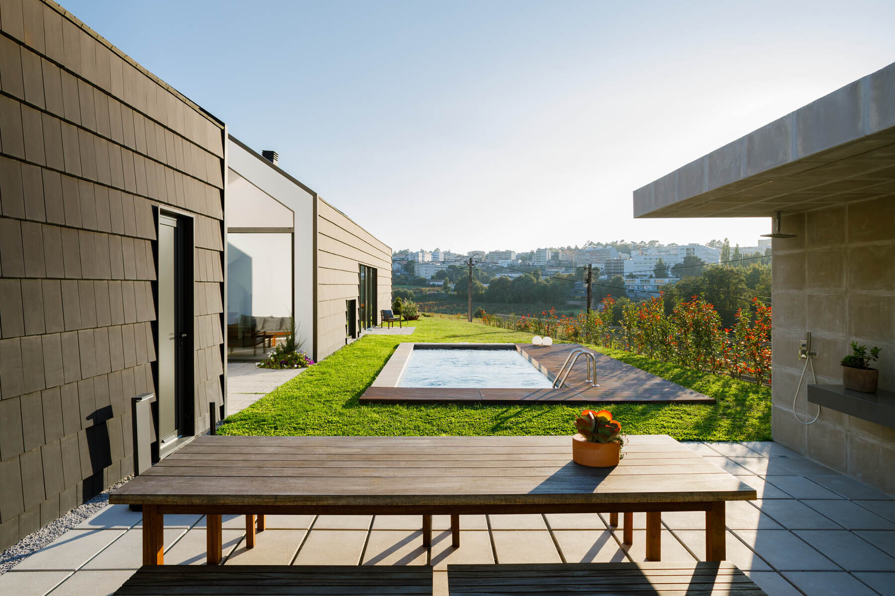 A central void opens the home to a patio, pool, and outdoor dining area, blending indoor living with open air spaces.