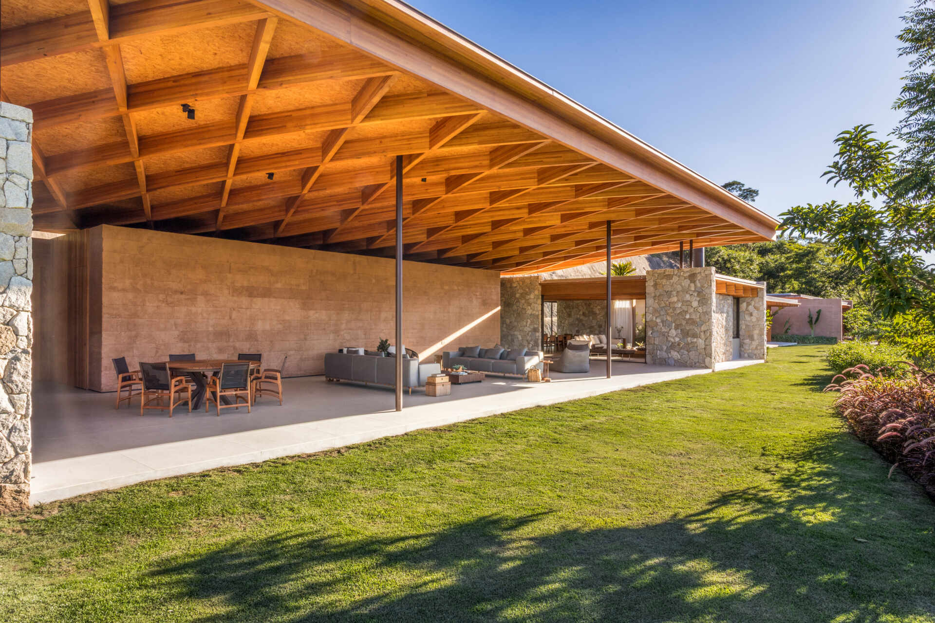 A sweeping wooden grid roof curves across the social spaces, supported by only eight slim metal pillars. It feels light and airy, framing views and glowing warmly at night.
