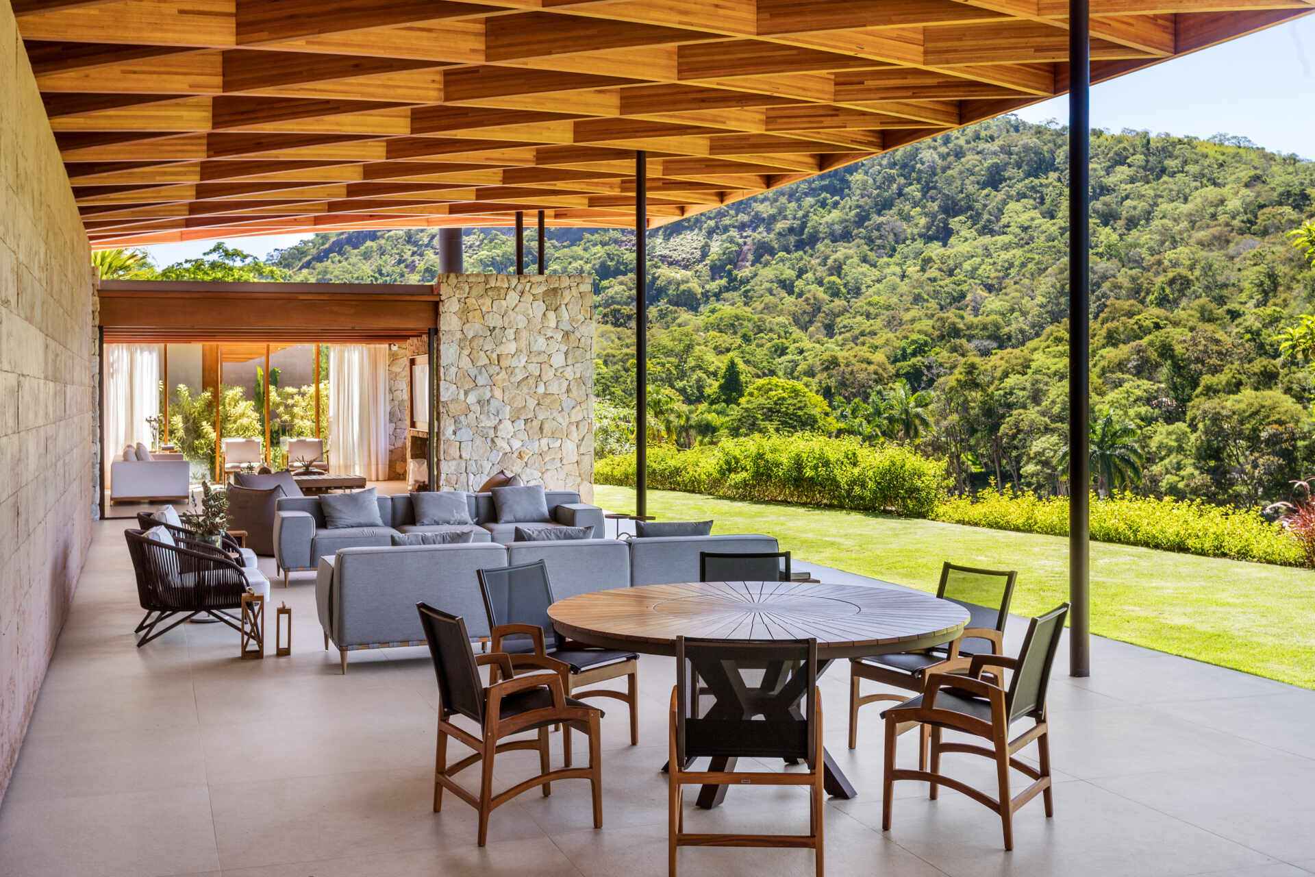 A sweeping wooden grid roof curves across the social spaces, supported by only eight slim metal pillars. It feels light and airy, framing views and glowing warmly at night.