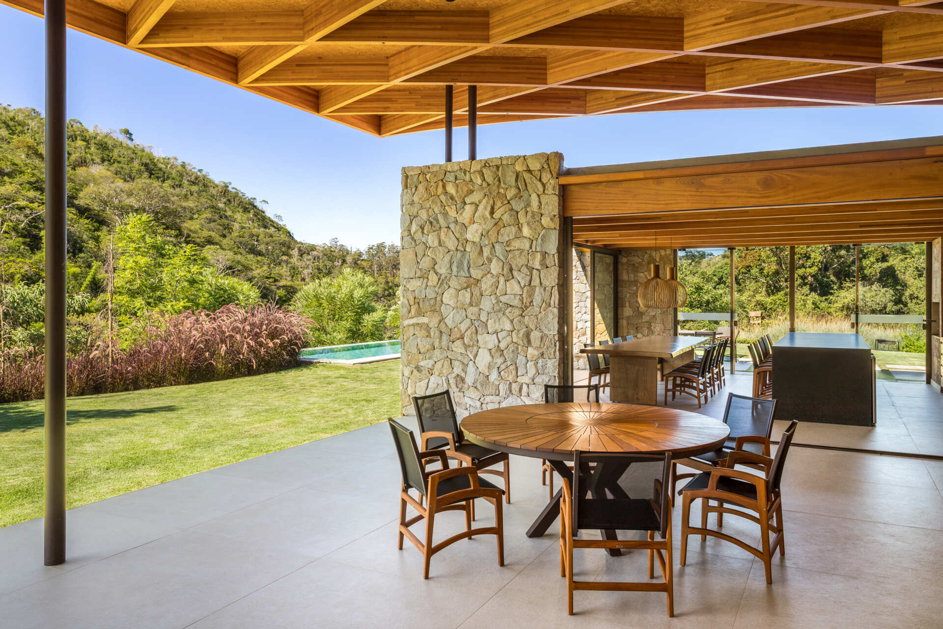 A sweeping wooden grid roof curves across the social spaces, supported by only eight slim metal pillars. It feels light and airy, framing views and glowing warmly at night.