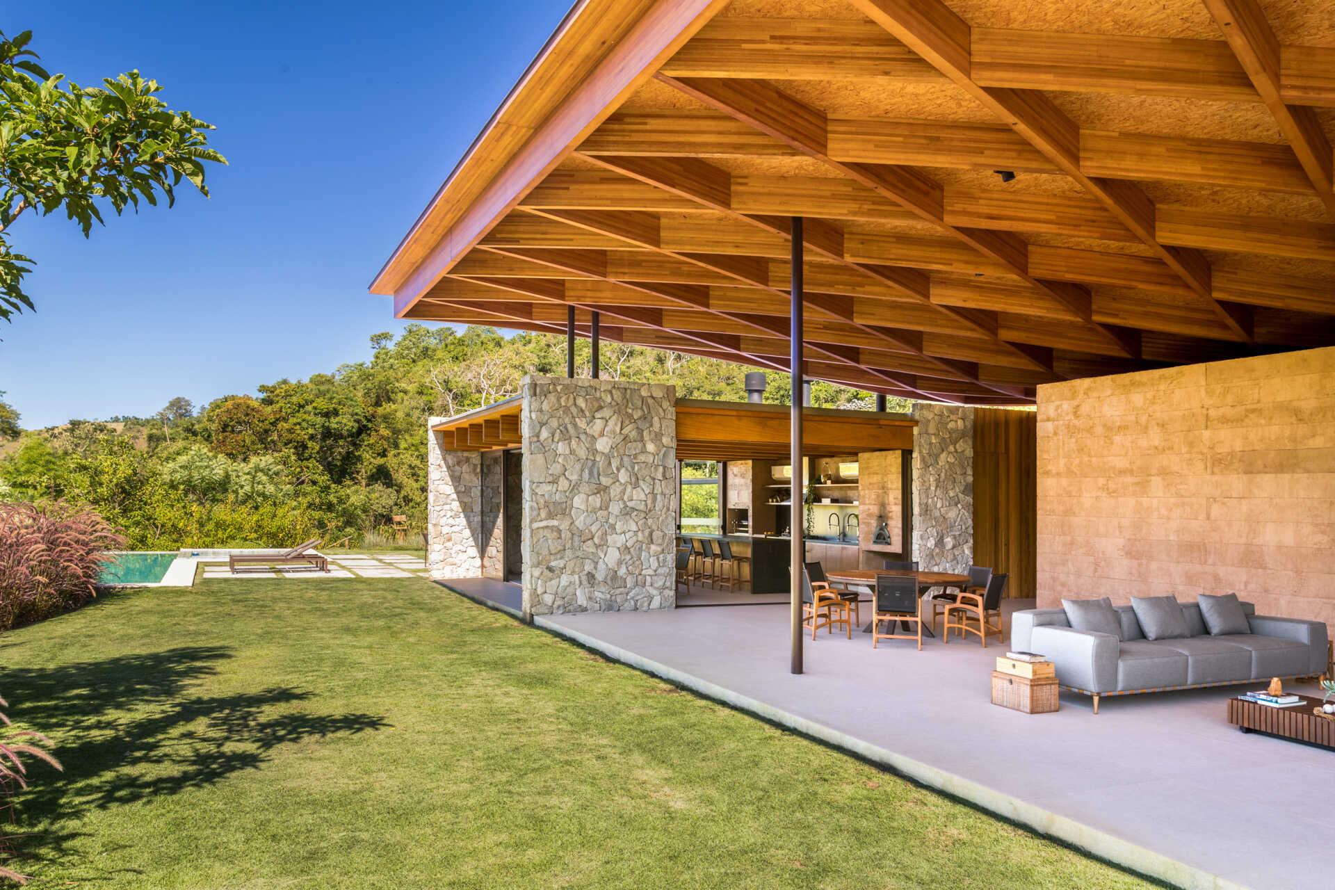 A sweeping wooden grid roof curves across the social spaces, supported by only eight slim metal pillars. It feels light and airy, framing views and glowing warmly at night.