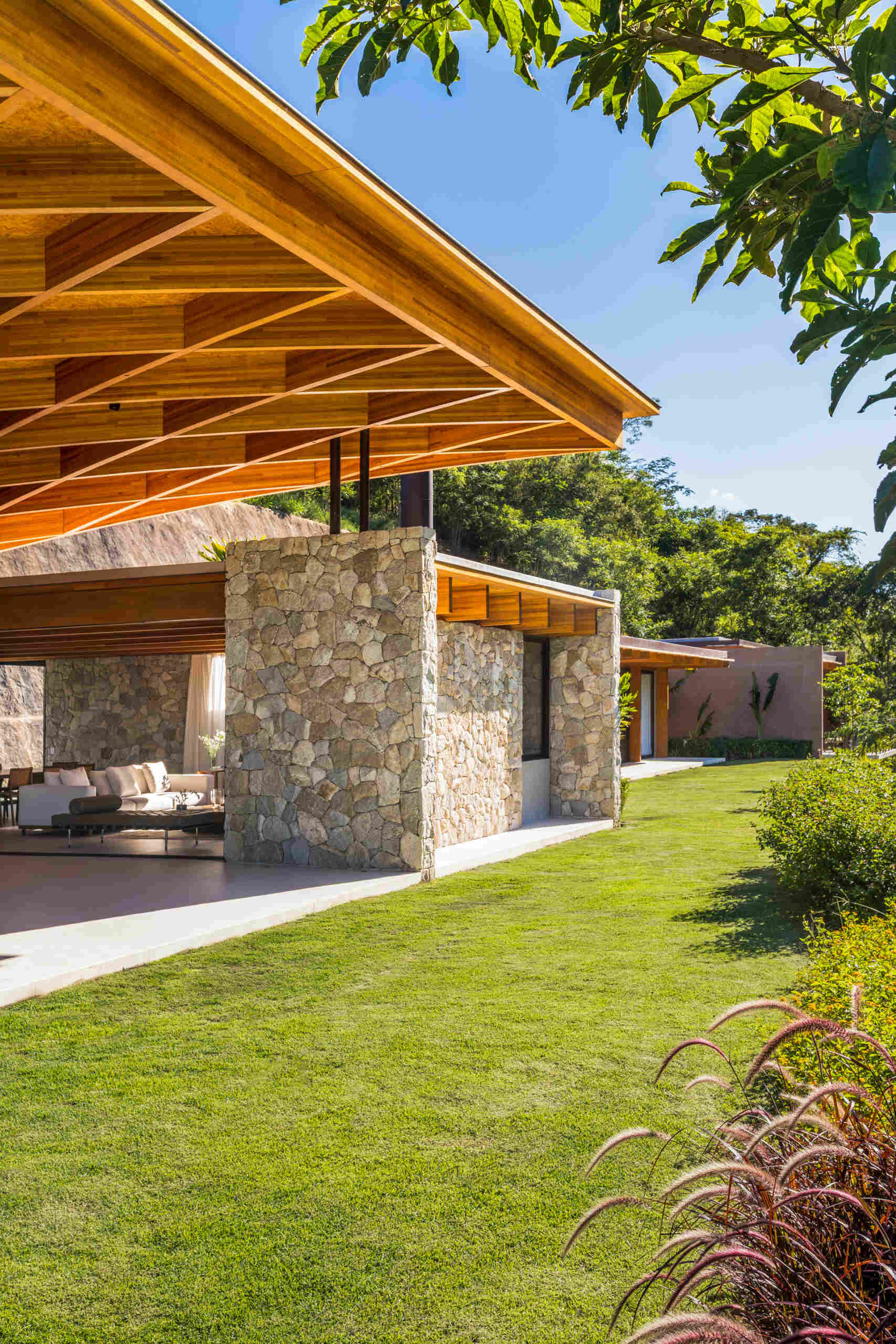 A sweeping wooden grid roof curves across the social spaces, supported by only eight slim metal pillars. It feels light and airy, framing views and glowing warmly at night.