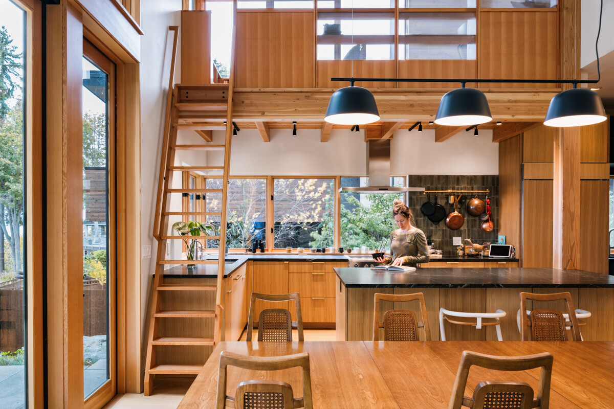 A modern kitchen with white oak cabinets and black soapstone counters, connected seamlessly to indoor and outdoor spaces.