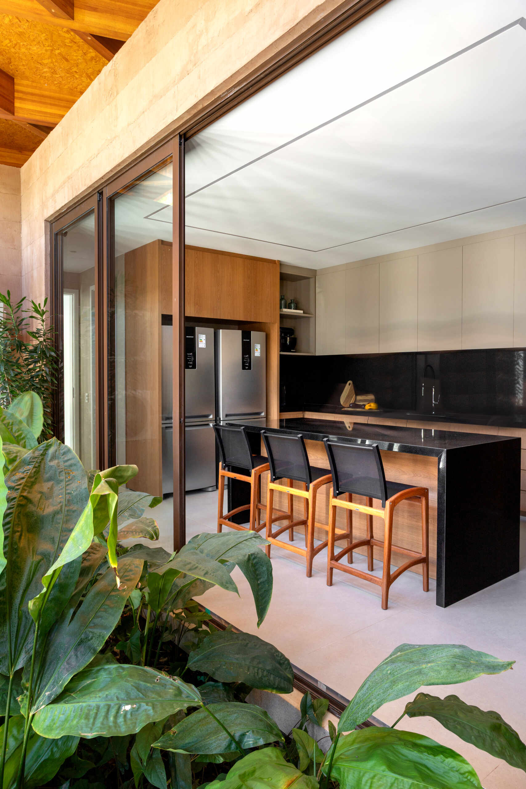 The kitchen pairs warm wood cabinetry with sleek black counters, keeping a modern yet welcoming feel. A long island anchors the space with stools for casual breakfasts or conversation while cooking.