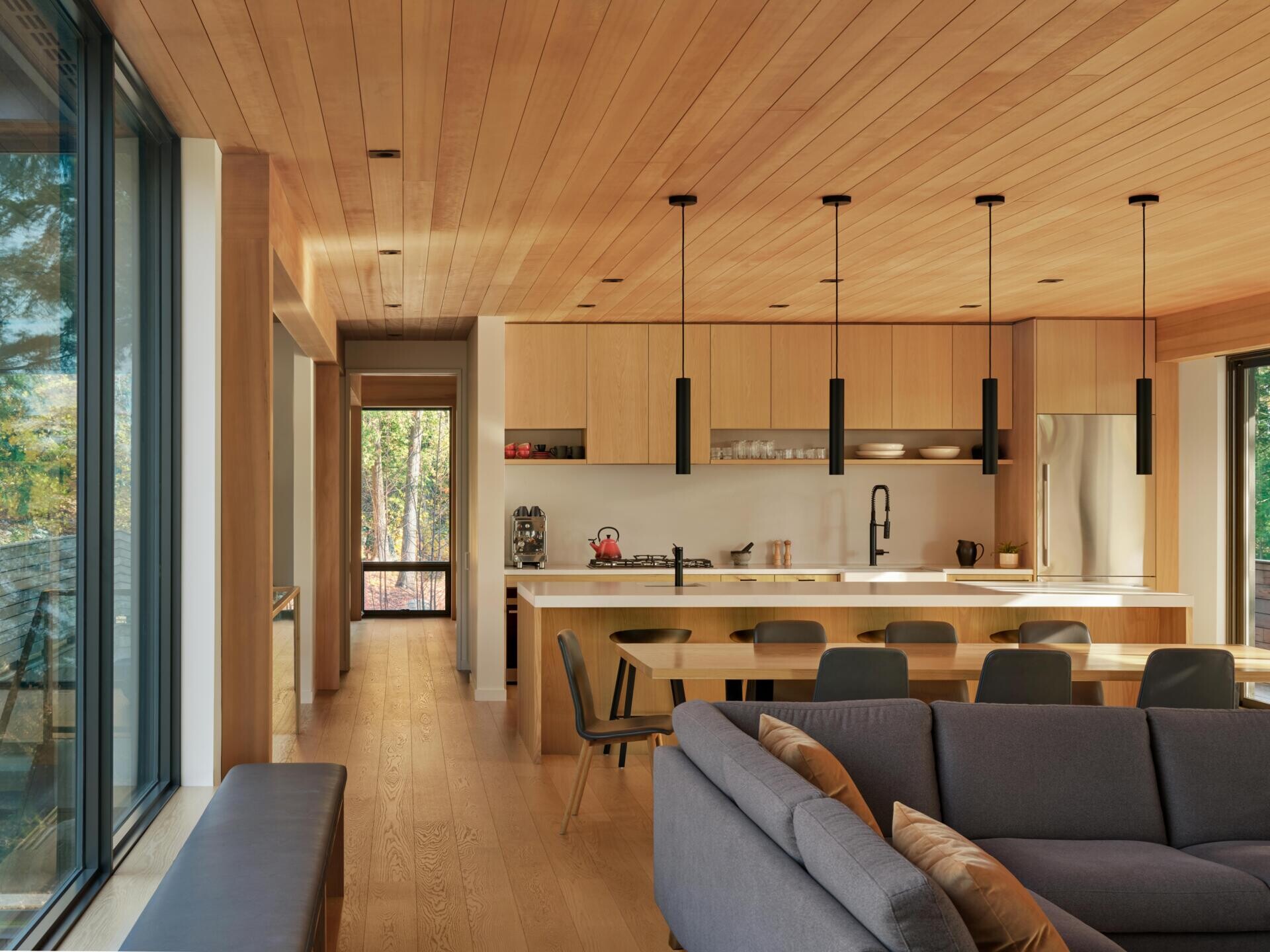 White oak cabinetry, stone surfaces, and a long island create a clean, functional kitchen that blends effortlessly into the open living space.
