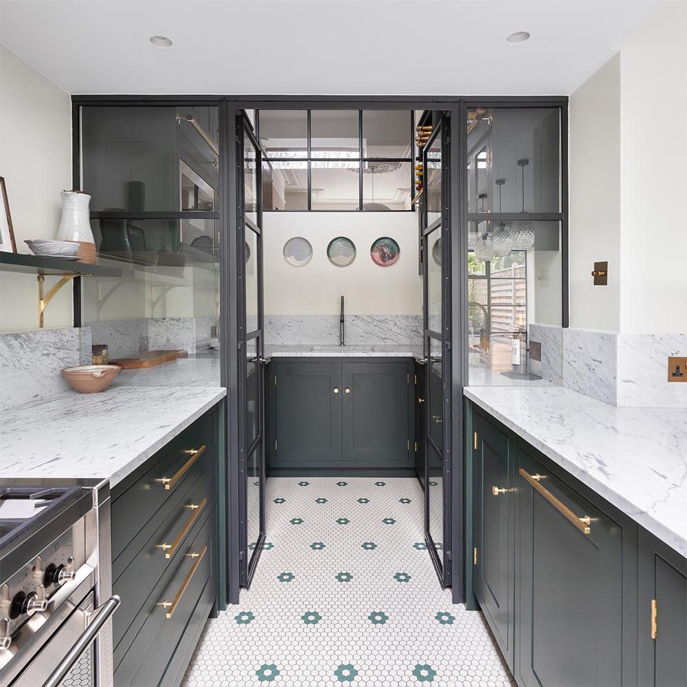A glass enclosed walk in pantry brings daylight deeper into the kitchen while adding a functional storage space.