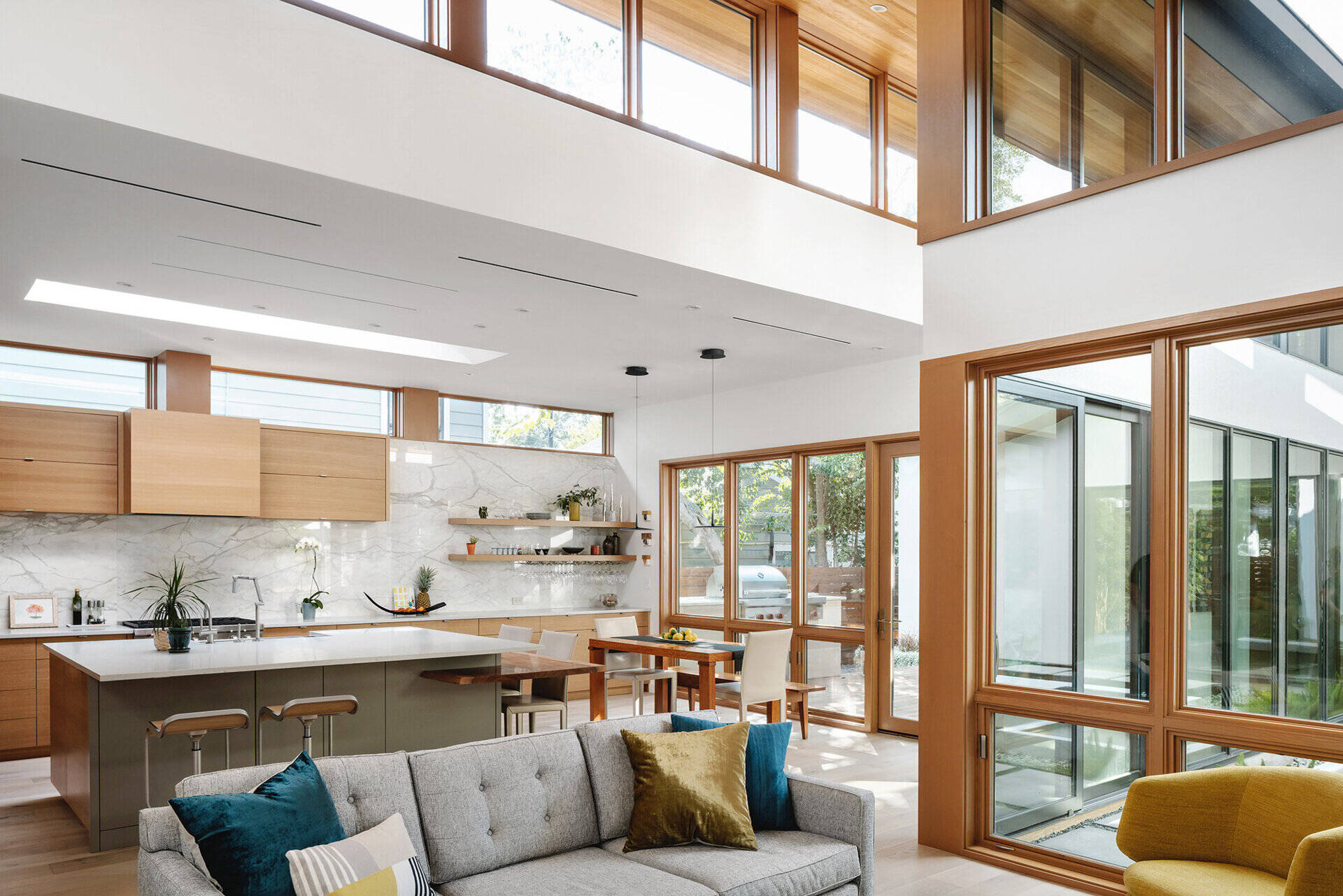 Minimalist wood cabinets, a marble backsplash, and a large kitchen island define the heart of this Austin home, where clean materials and open planning create a relaxed space for cooking and gathering.
