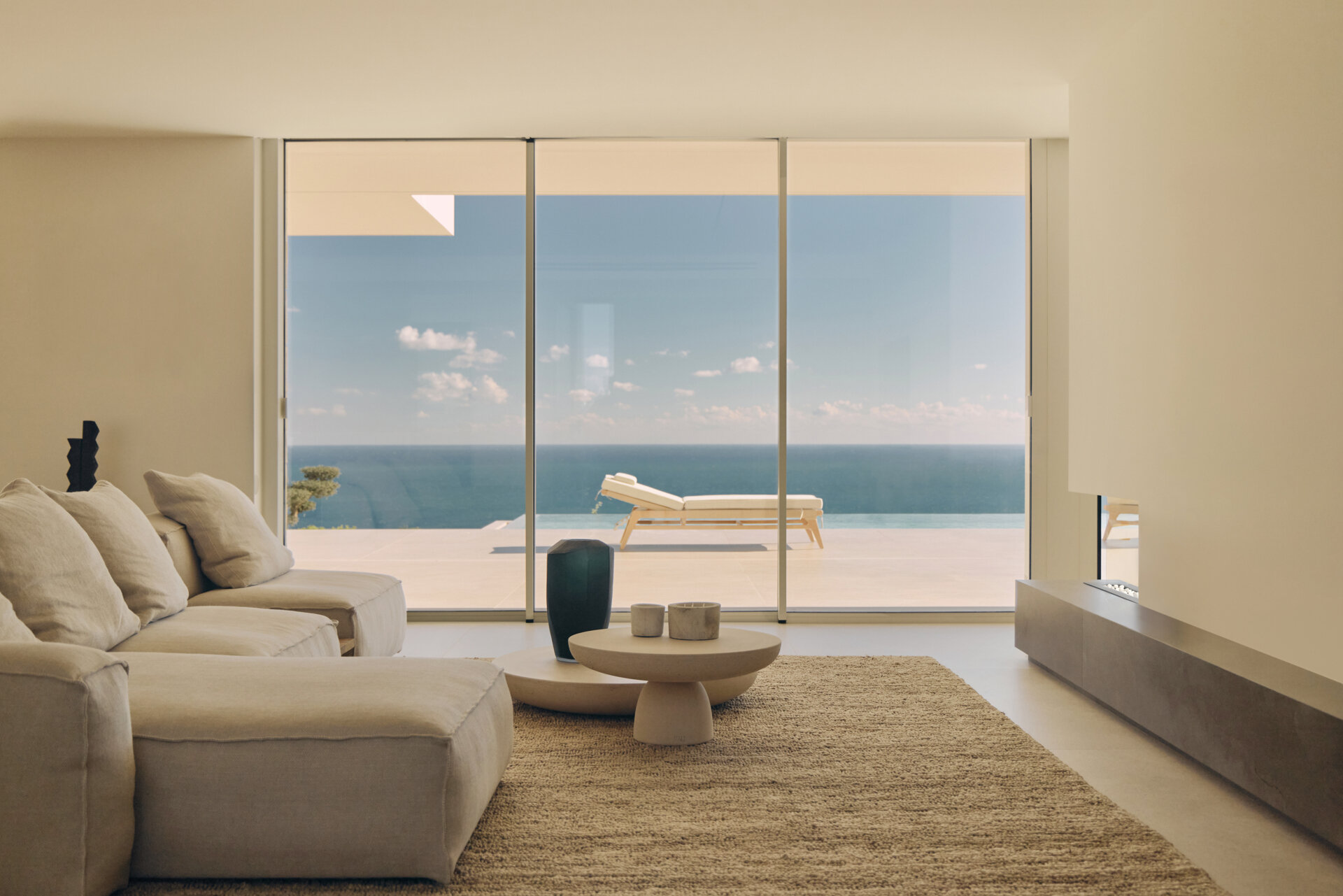 Inside the main living spaces, the connection to the sea becomes constant. The furniture is arranged to face the fireplace, while a sitting area is located on the other side of the fireplace.
