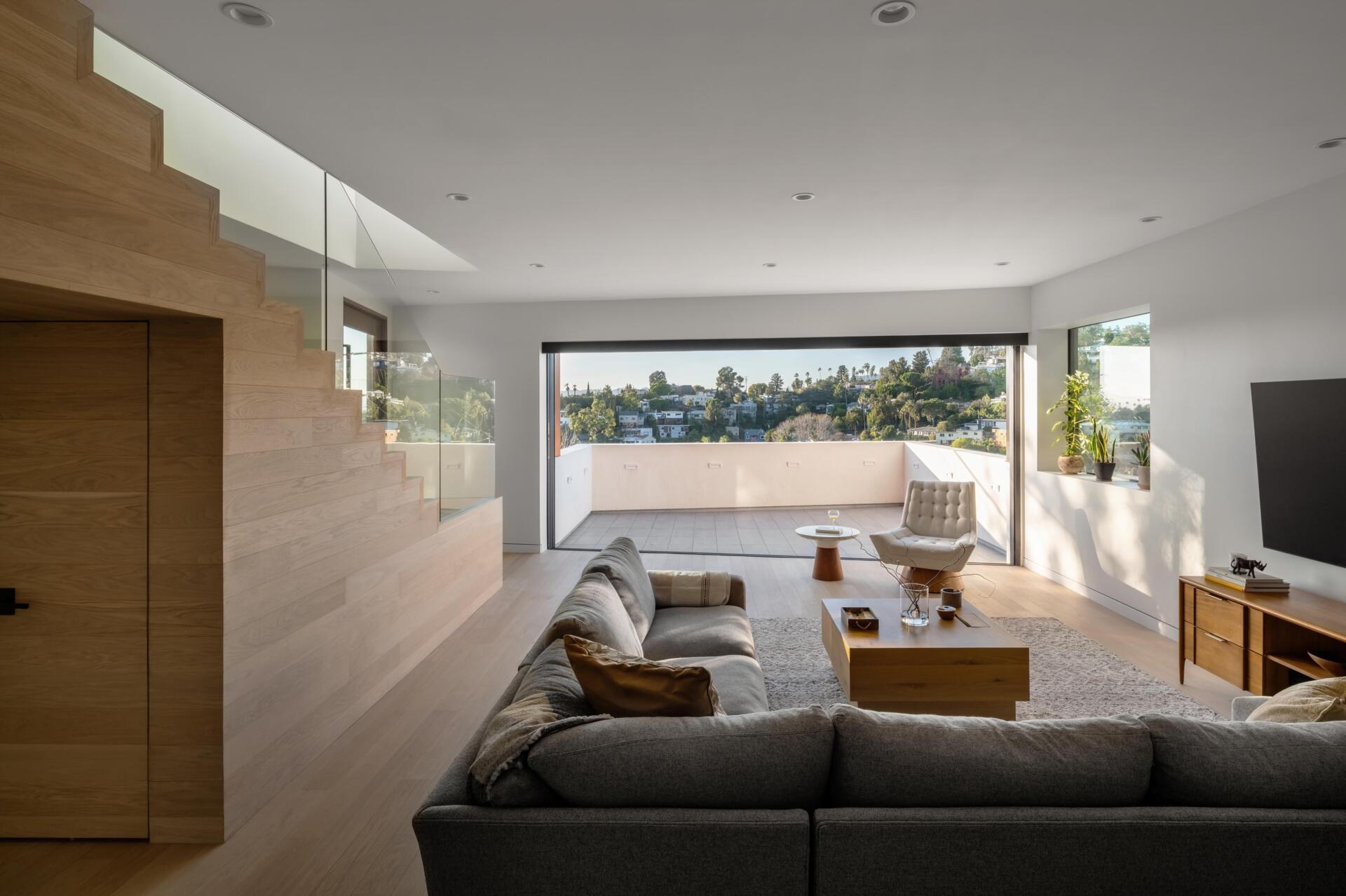 The living room sits within an open layout that encourages movement between spaces. It feels connected to the rest of the home without losing its own sense of place. Large openings frame views of the hills and reservoir, bringing the landscape into everyday living.
