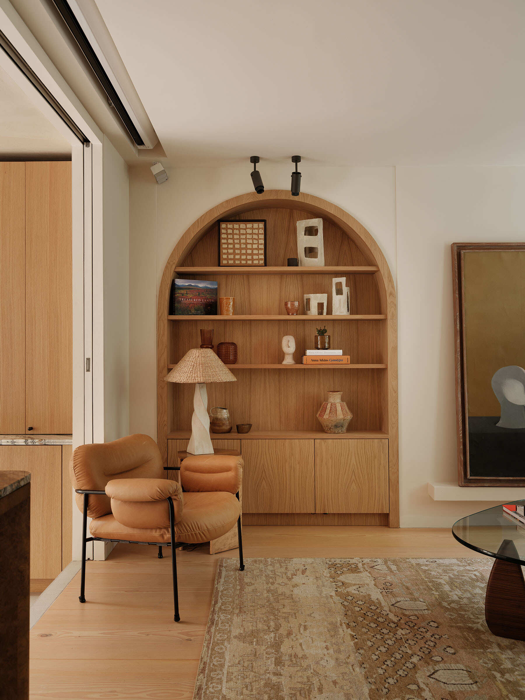 The living area benefits from the expanded footprint created by the extension. An arched shelving unit draws reference from the doors to the backyard. 