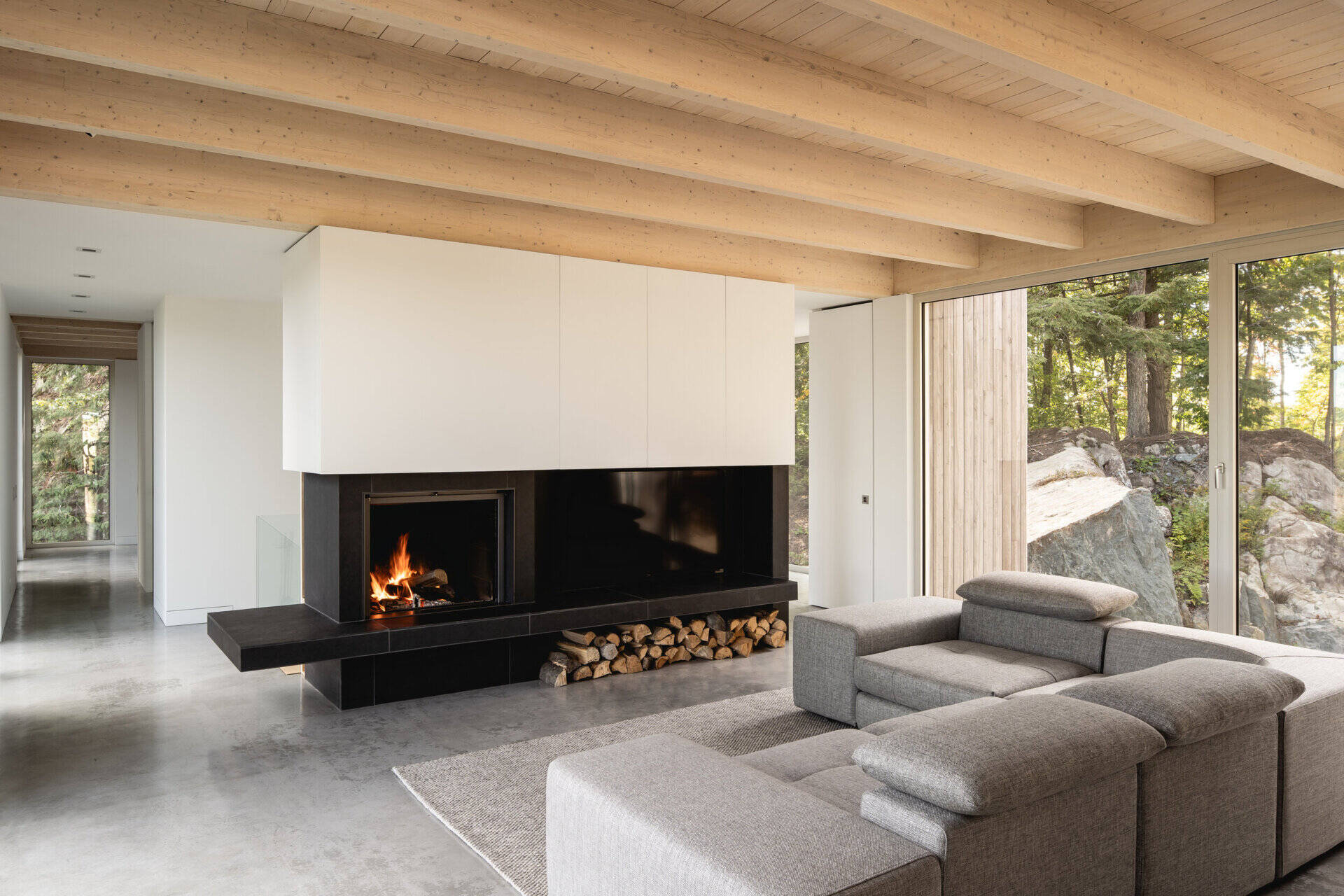 Los ventanales rodean la sala de estar, inundando el espacio abierto con luz natural y ofreciendo vistas al dosel del bosque.
