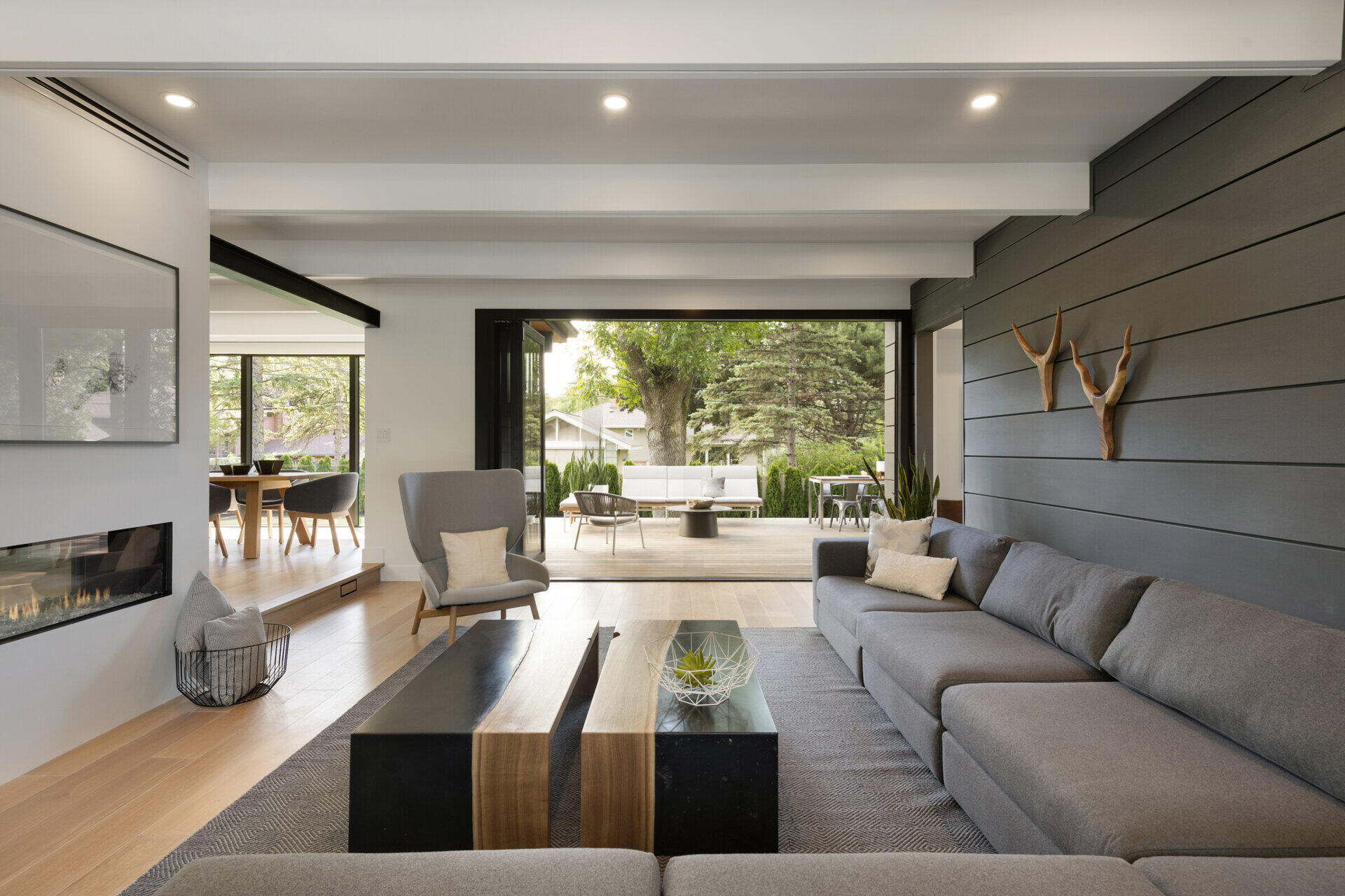 La sala familiar está ubicada en la parte trasera de la casa y ofrece un área de reunión cómoda pero sofisticada. Una pared con paneles grises ancla el espacio, reflejando el sofá a juego, mientras que una chimenea de doble cara crea una calidez visible desde la sala familiar y el comedor adyacente.